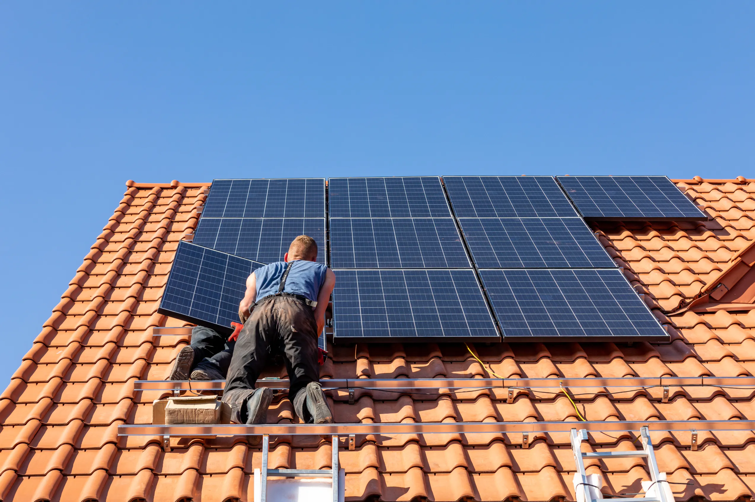 Installateur posant des panneaux photovoltaïques sur un toit en tuiles