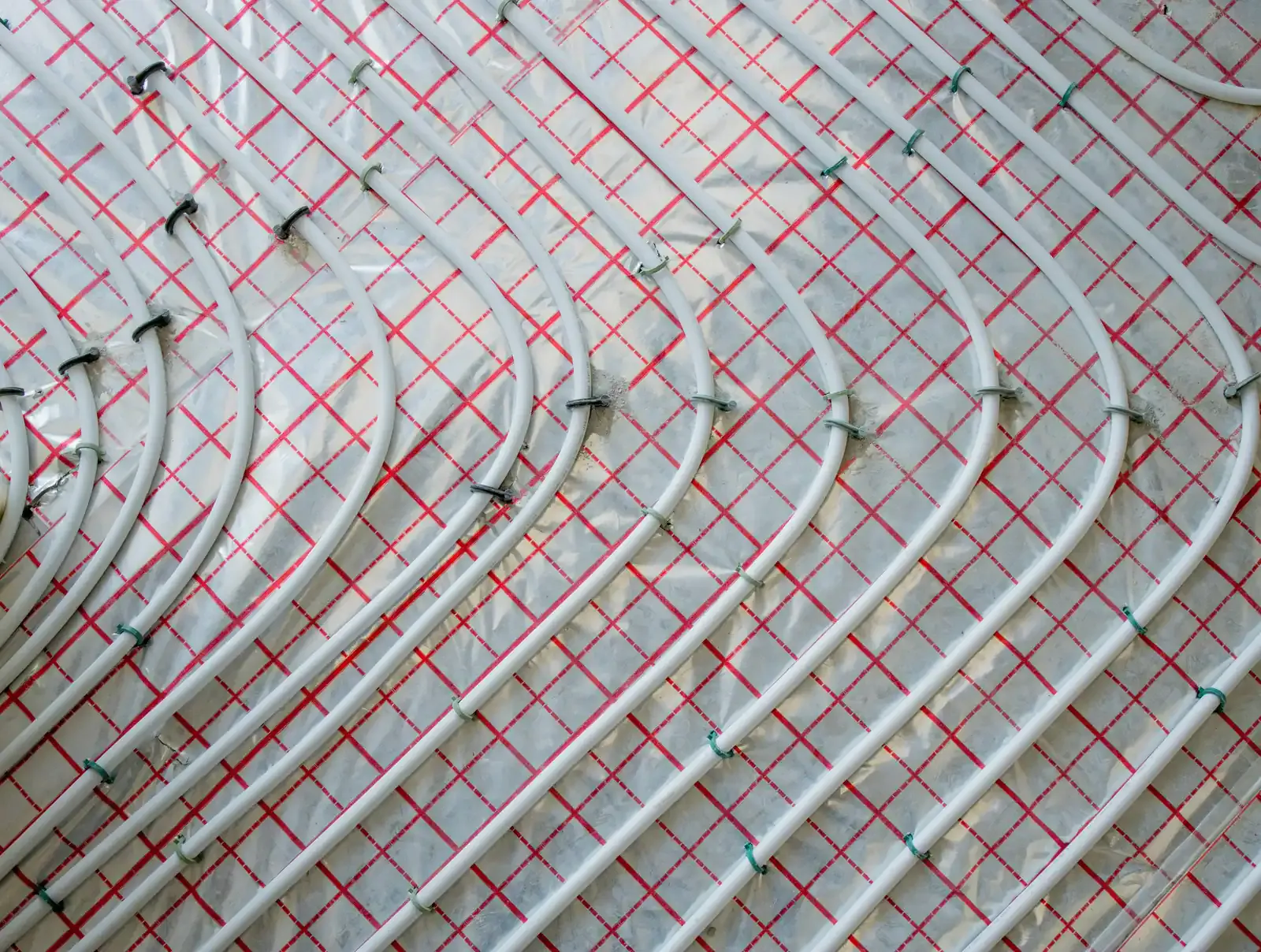 Tubes de plancher chauffant posés en serpentin sur un isolant quadrillé