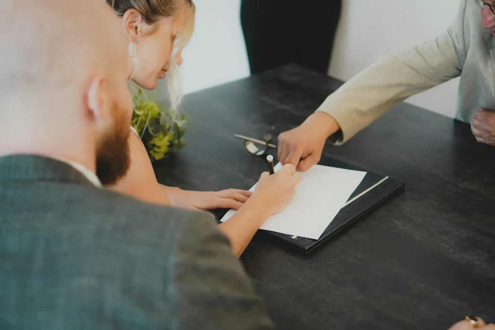 Couple signant un document à un bureau, en présence d'un conseiller