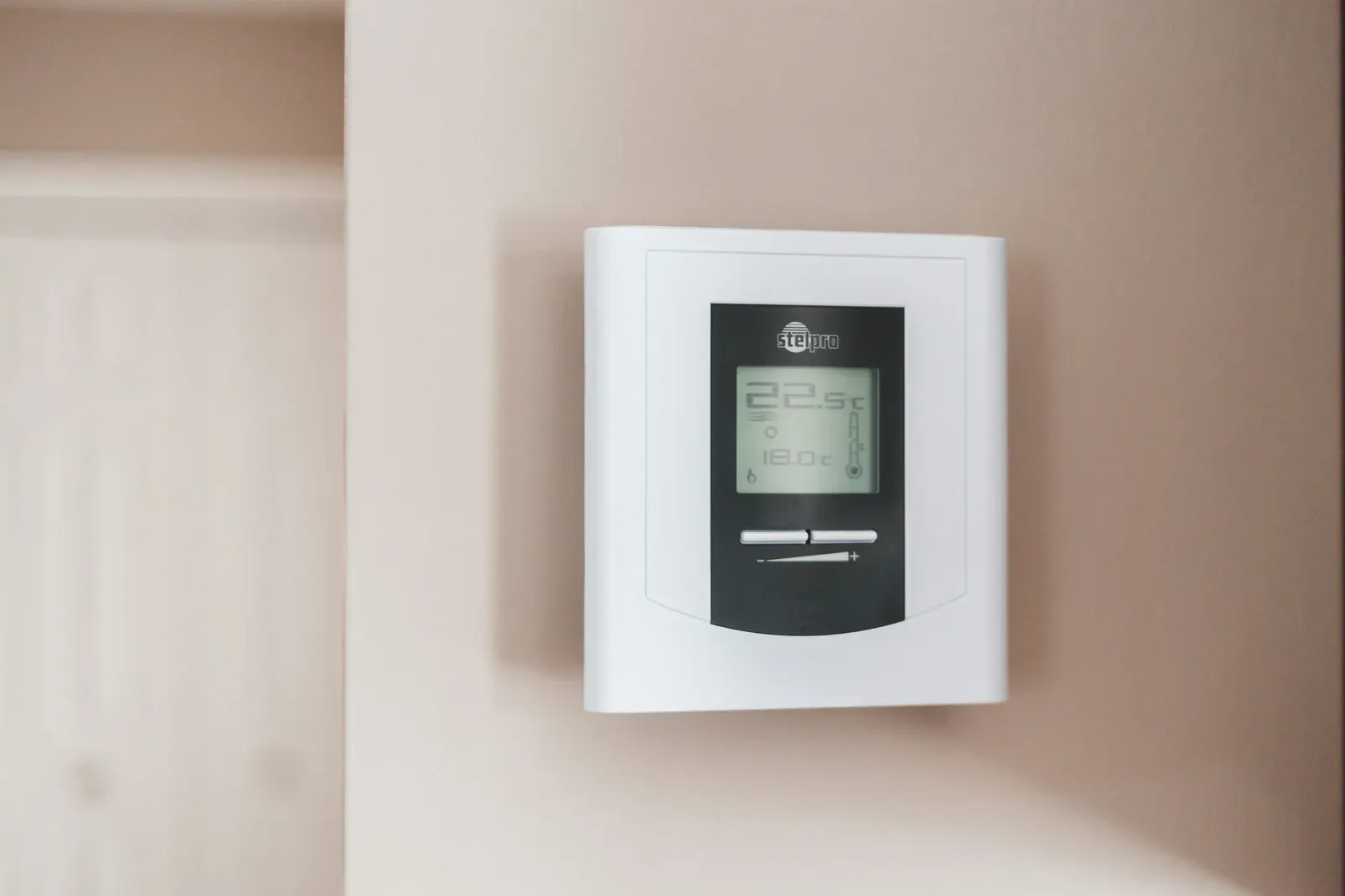Thermostat d'ambiance numérique blanc fixé au mur affichant 22,5 °C