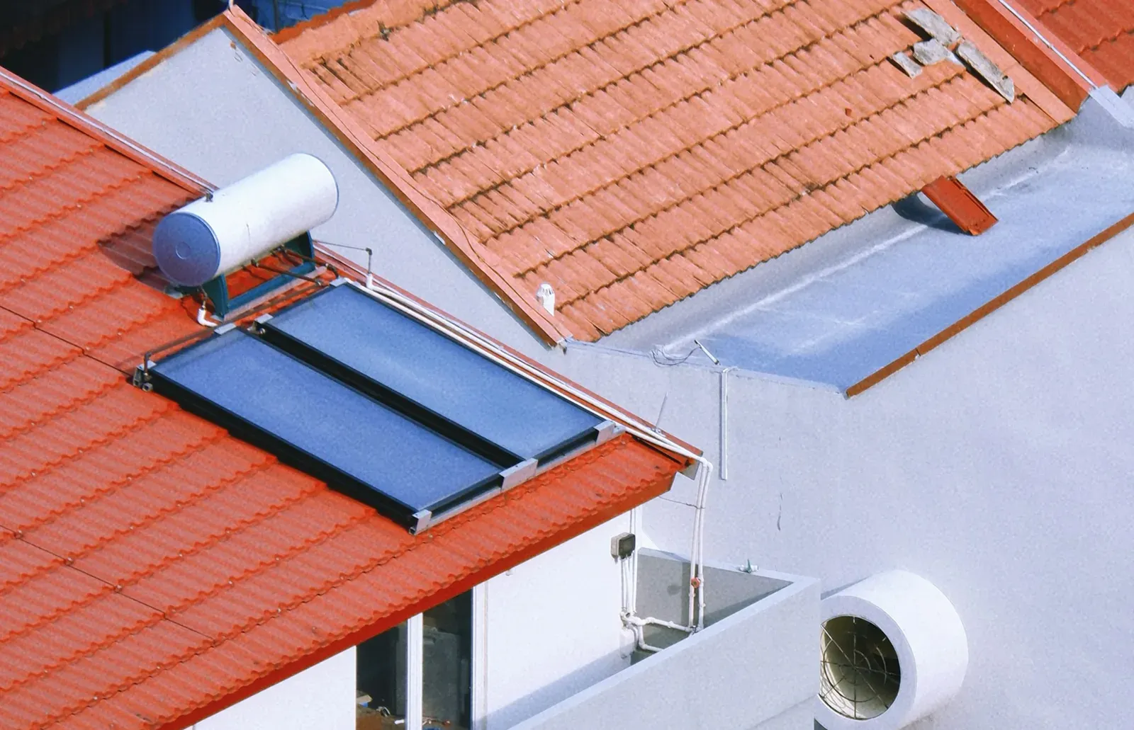 Deux capteurs solaires thermiques vitrés et leur ballon sur une toiture en tuiles