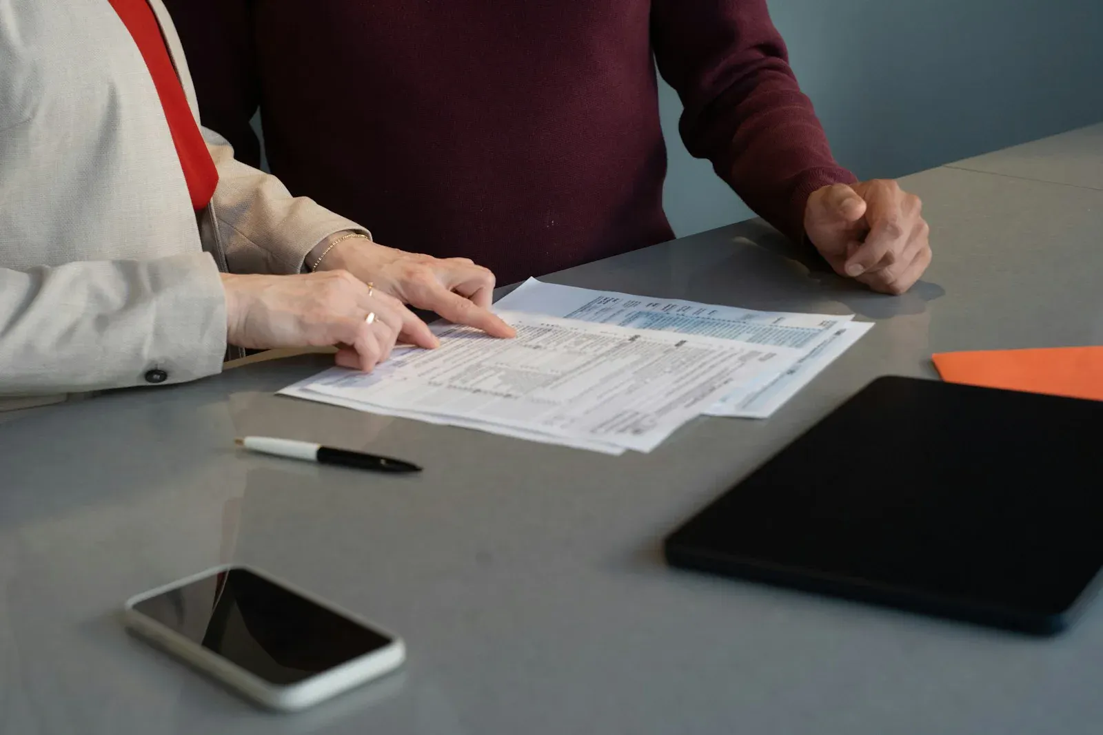 Deux personnes relisant des formulaires administratifs étalés sur une table