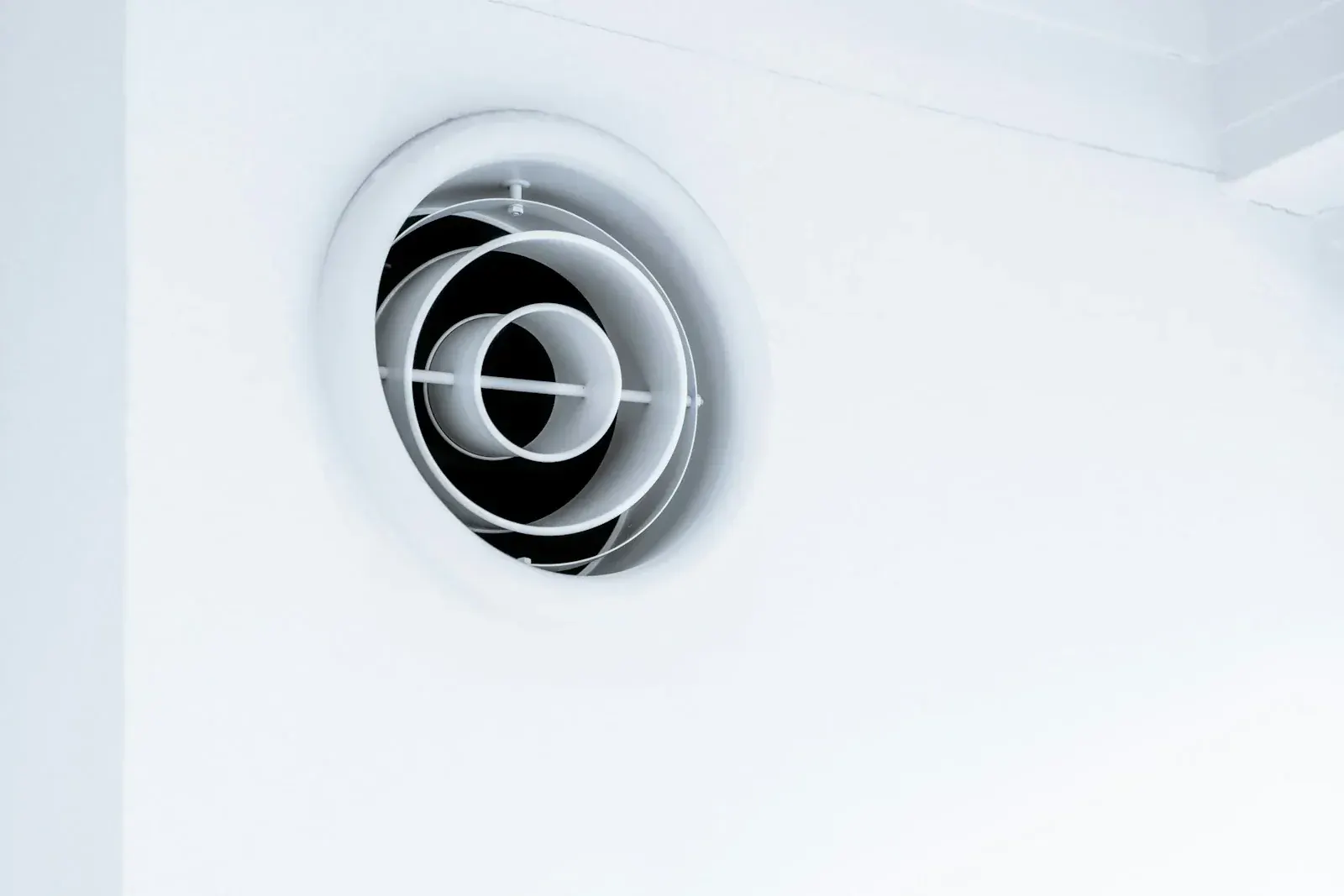 Bouche de ventilation ronde à disques réglables encastrée en haut d'un mur blanc