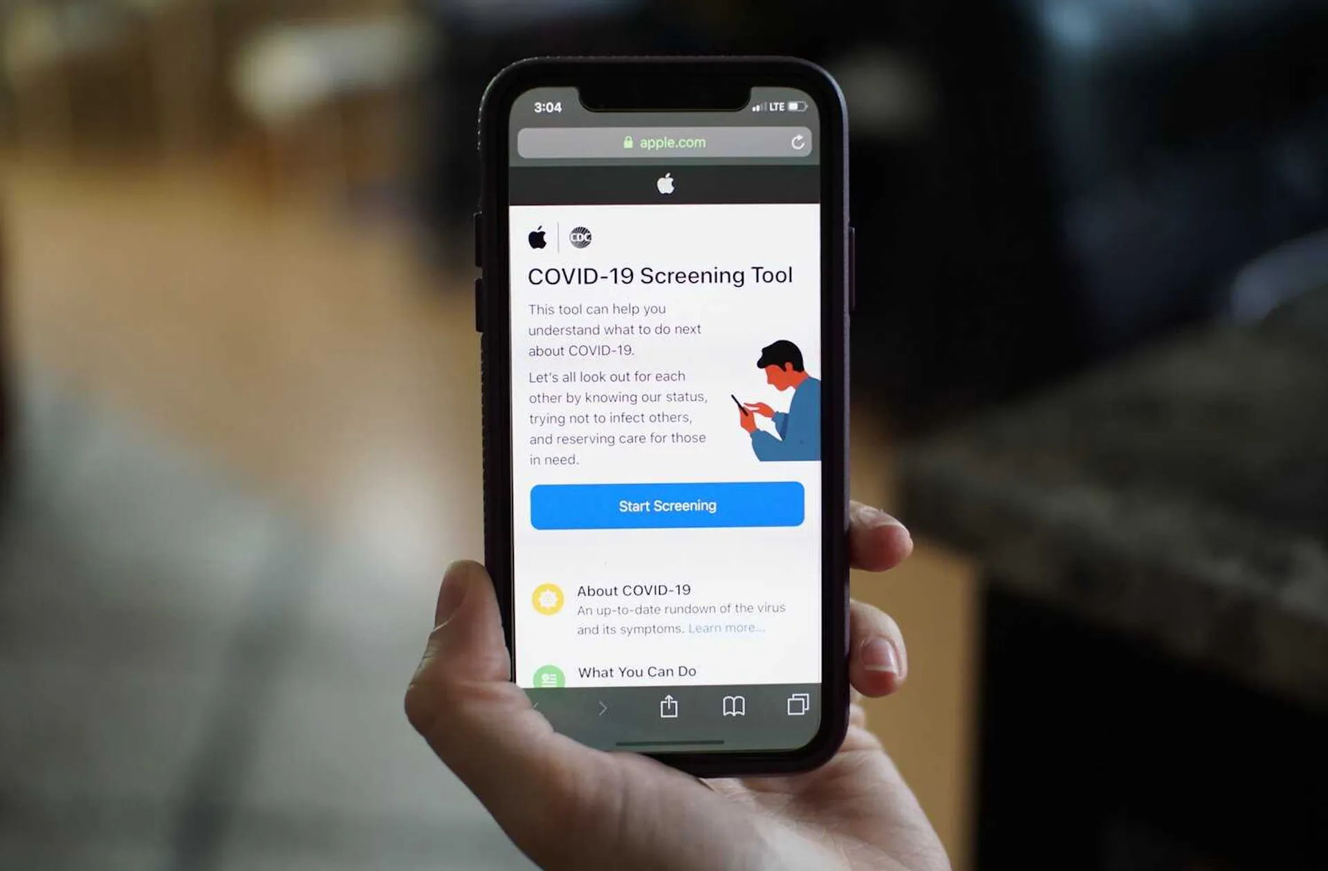 Hand holding a phone displaying a COVID-19 screening tool