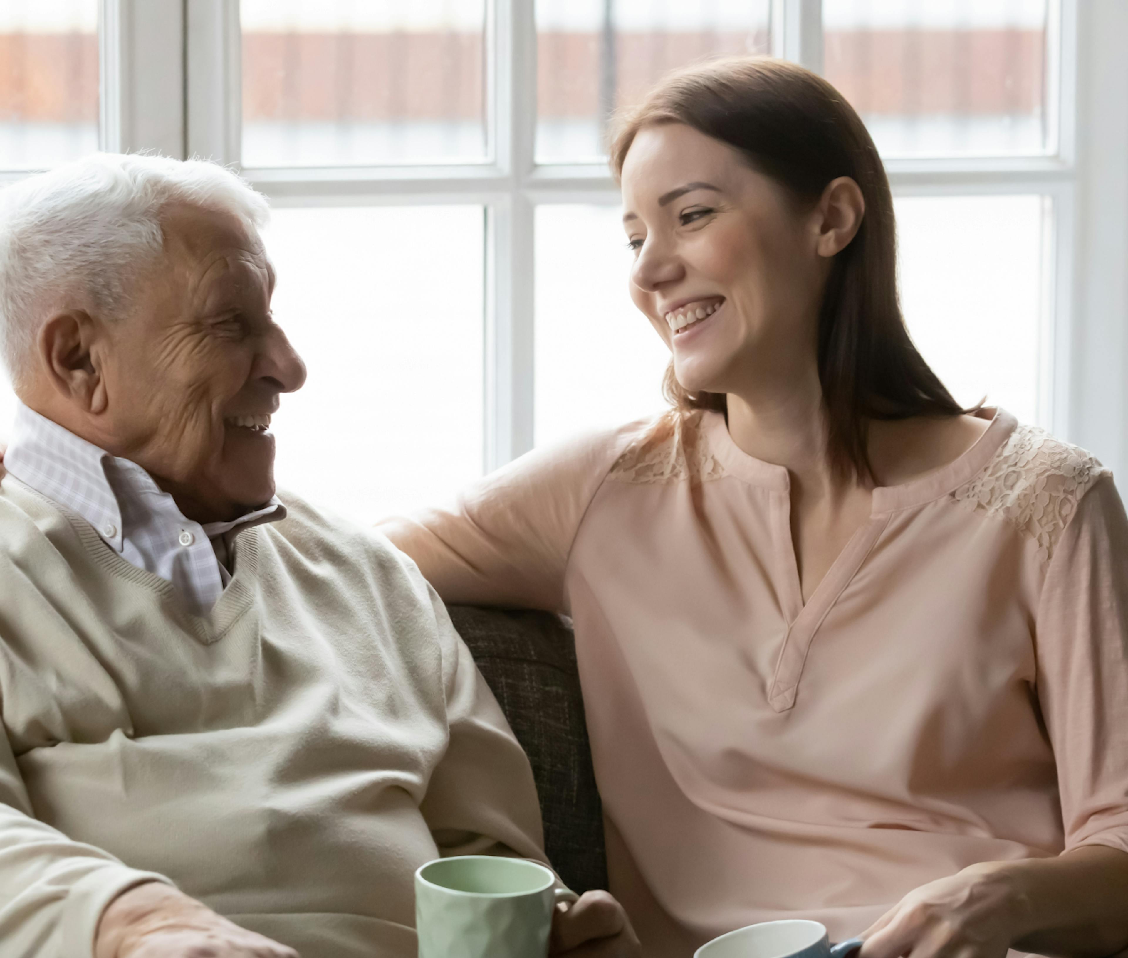 Happy mature man with grownup daughter chatting at home