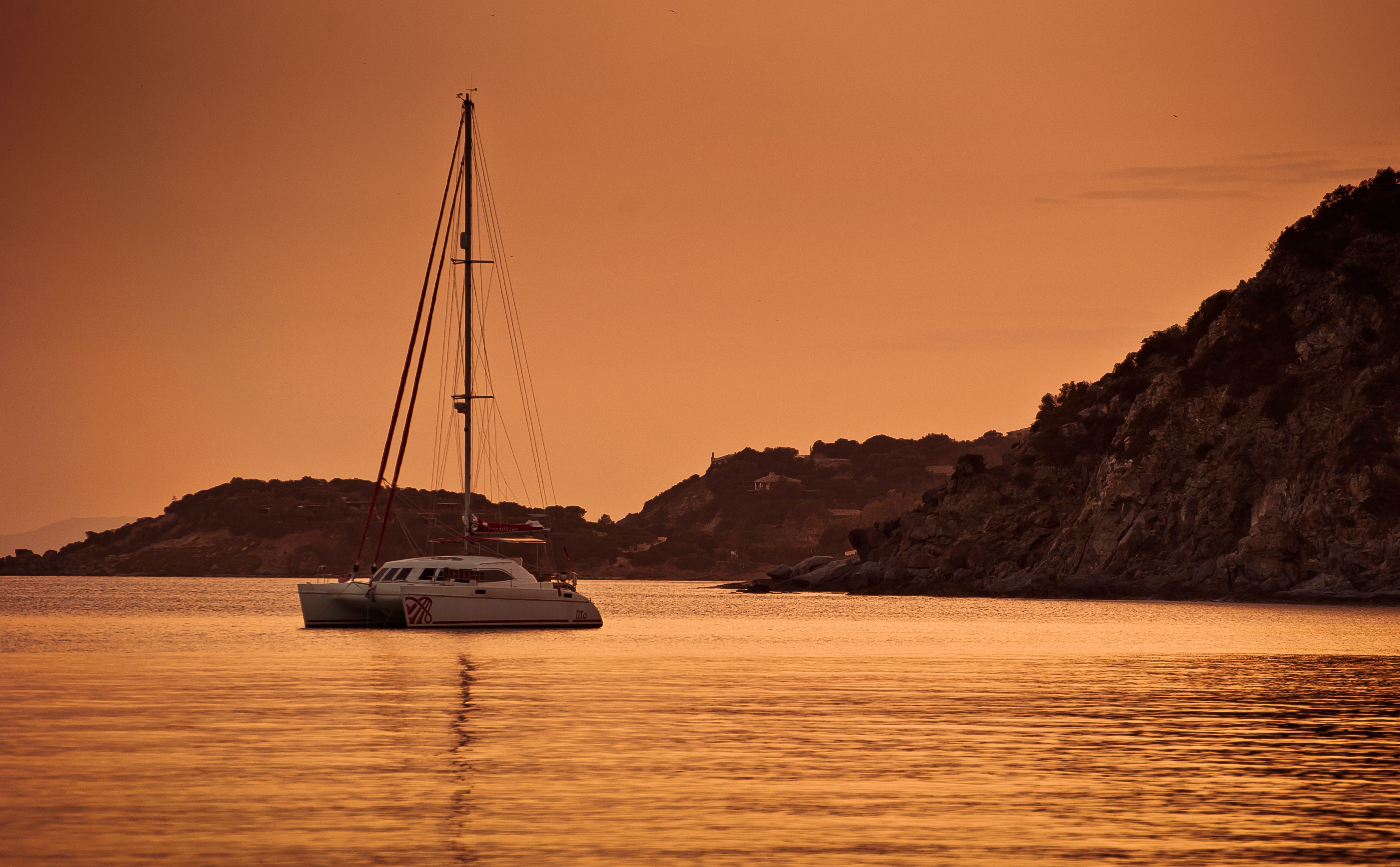 Catamaran anchored in a bay at sunset