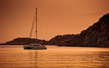 Catamaran anchored in a bay at sunset