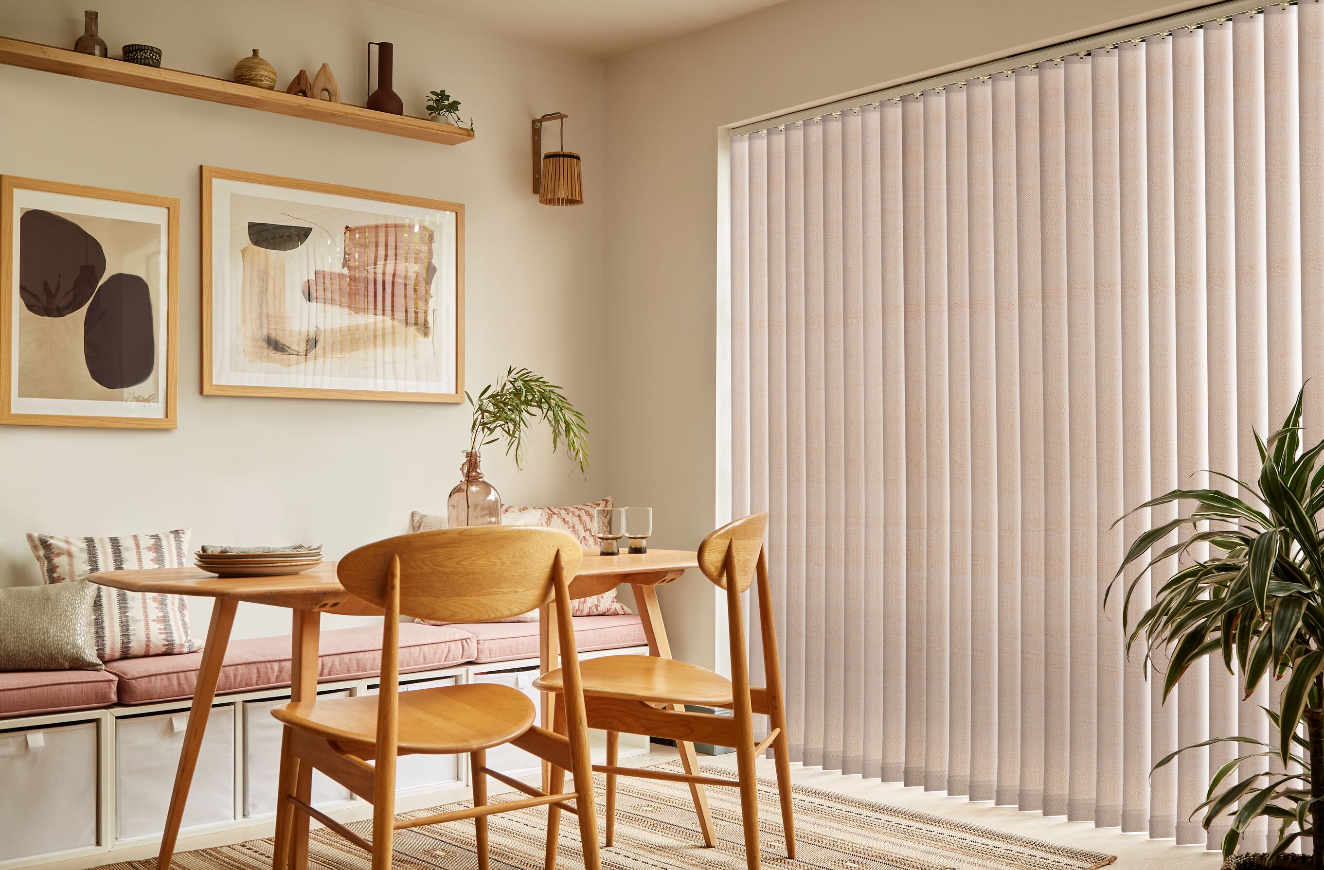 Light neutral vertical blinds covering patio doors in a modern dining room with oak furniture and natural textures.