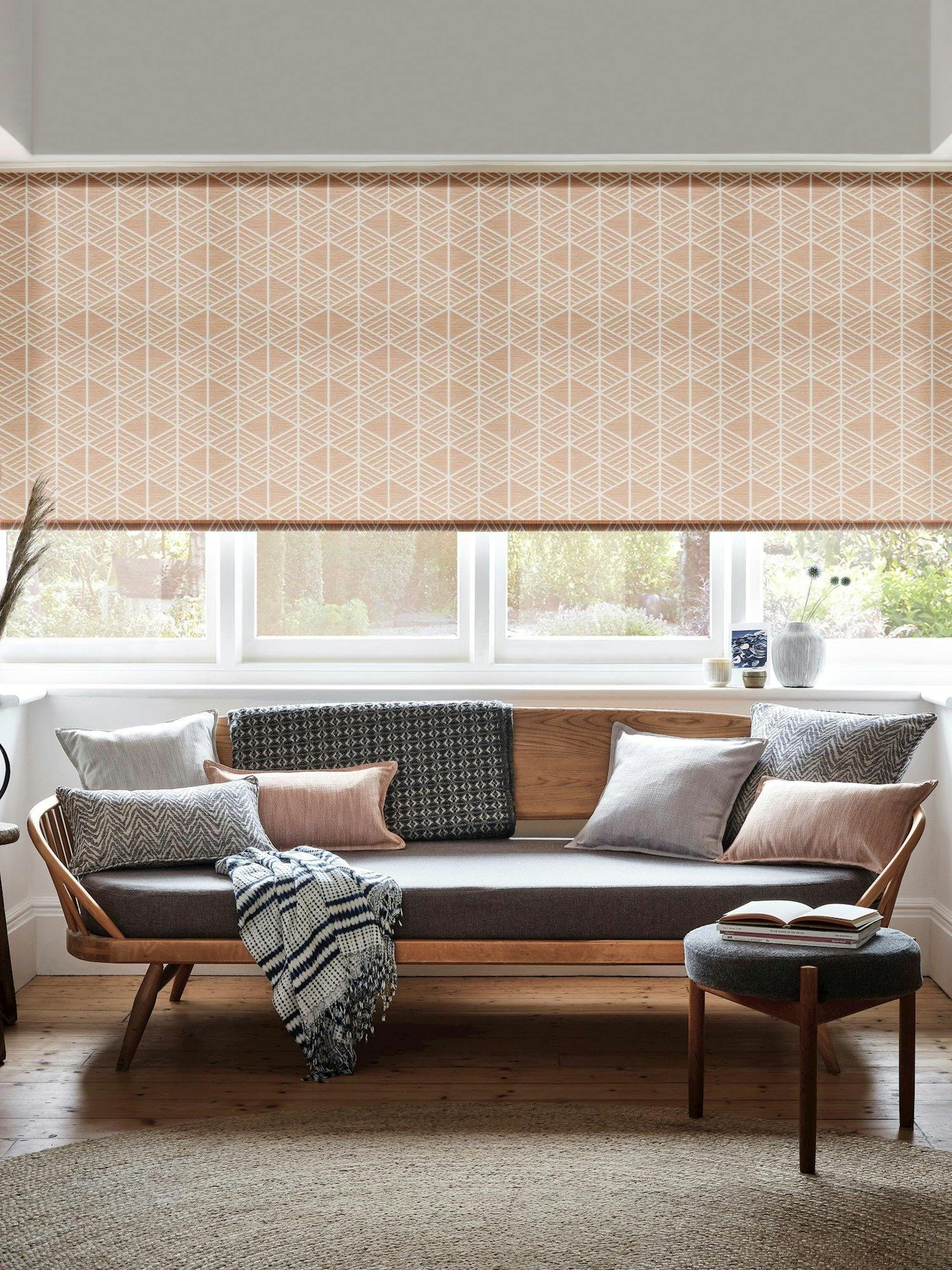 Roller blinds in a living room with a sofa facing away from the window and a small circular table next to the sofa.