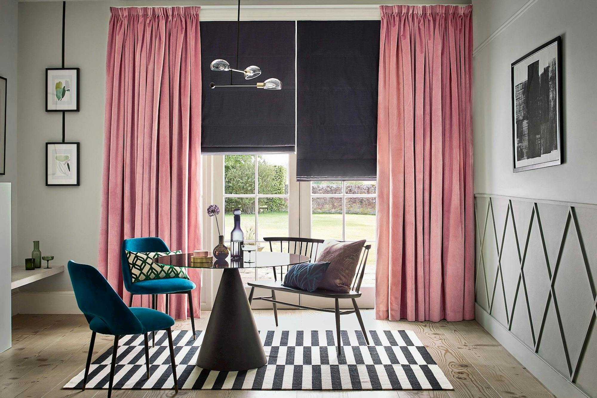Velvet, rose pink curtains over a dark roman blind in a modern living room
