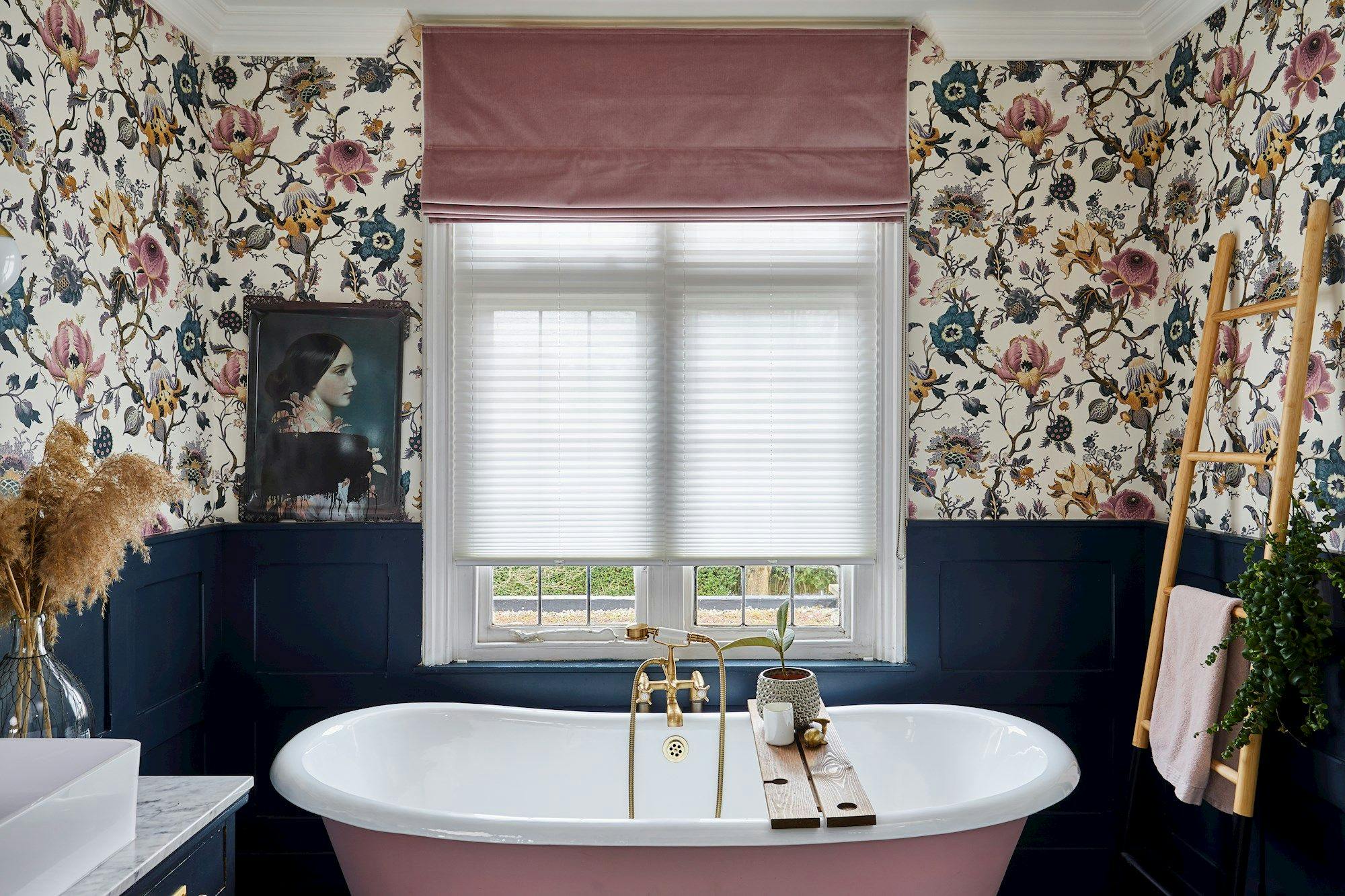 Rose pink, velvet roman blind over light, pleated blinds in a floral bathroom with rose pink and navy accents