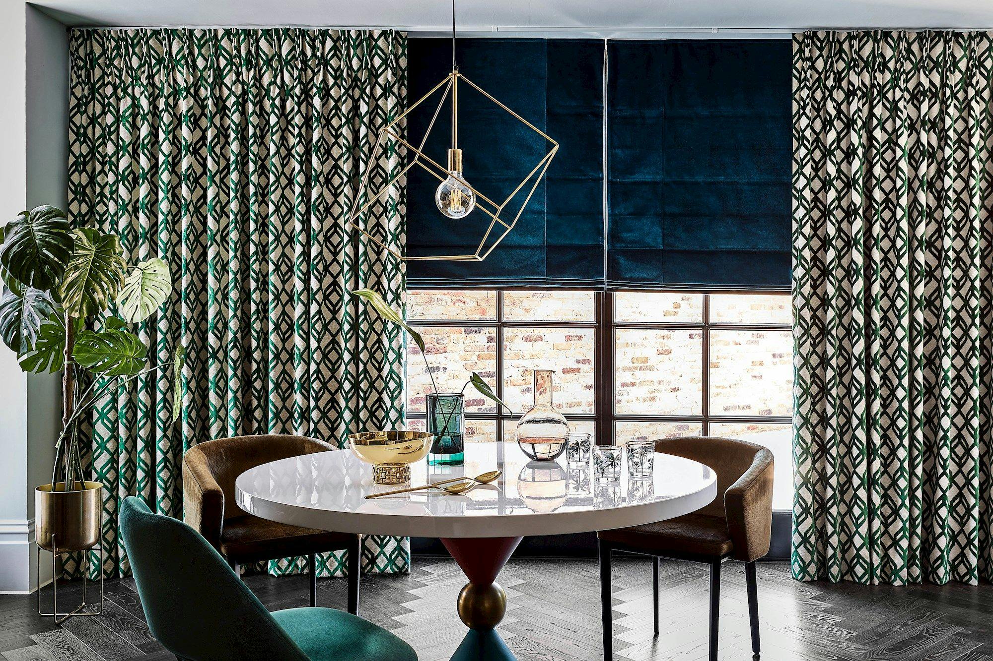 emerald and gold curtains on a large window paired with teal roman blinds in a dining room