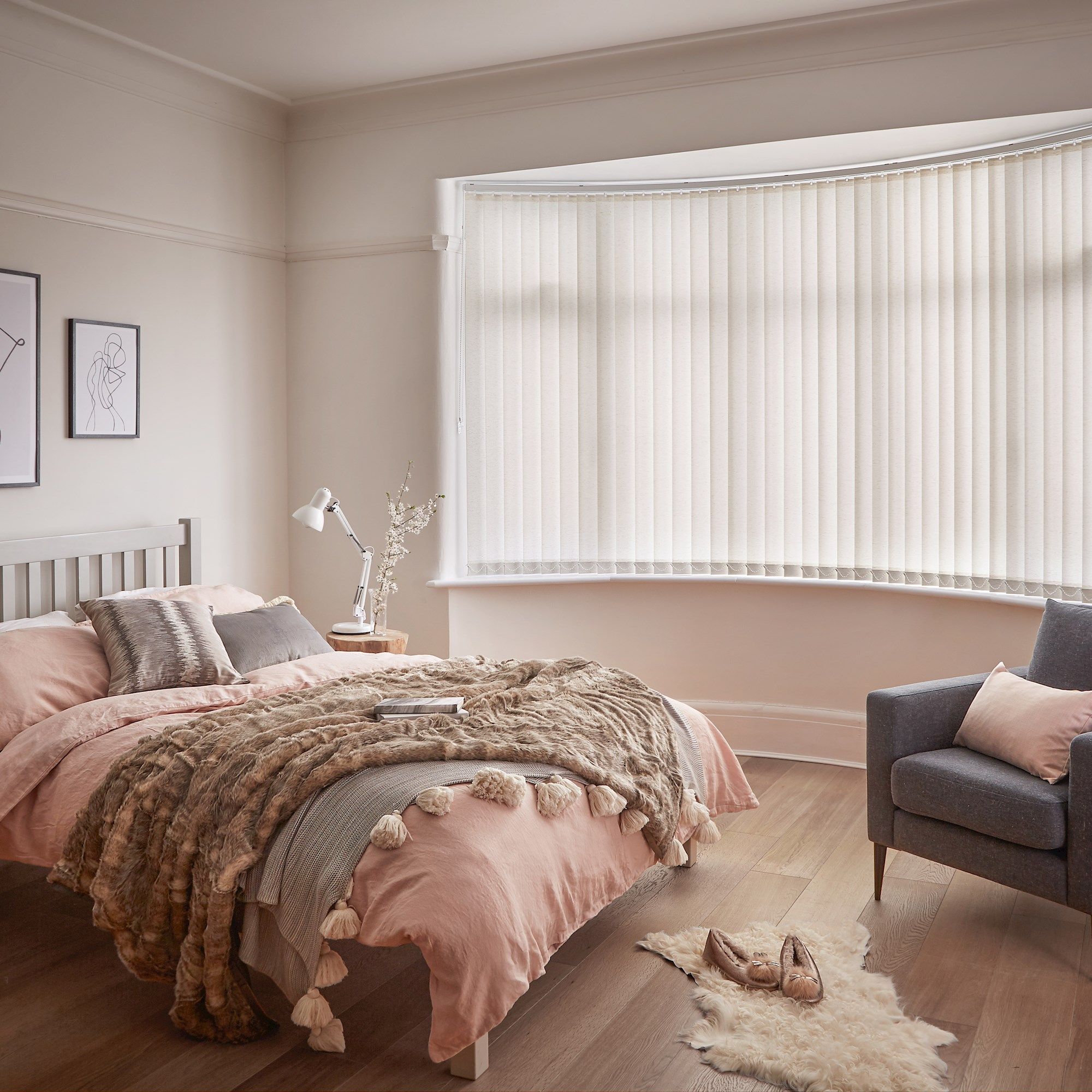 Minimal luxe bedroom with soft furnishings and a bow window dressed with light cream vertical blinds 