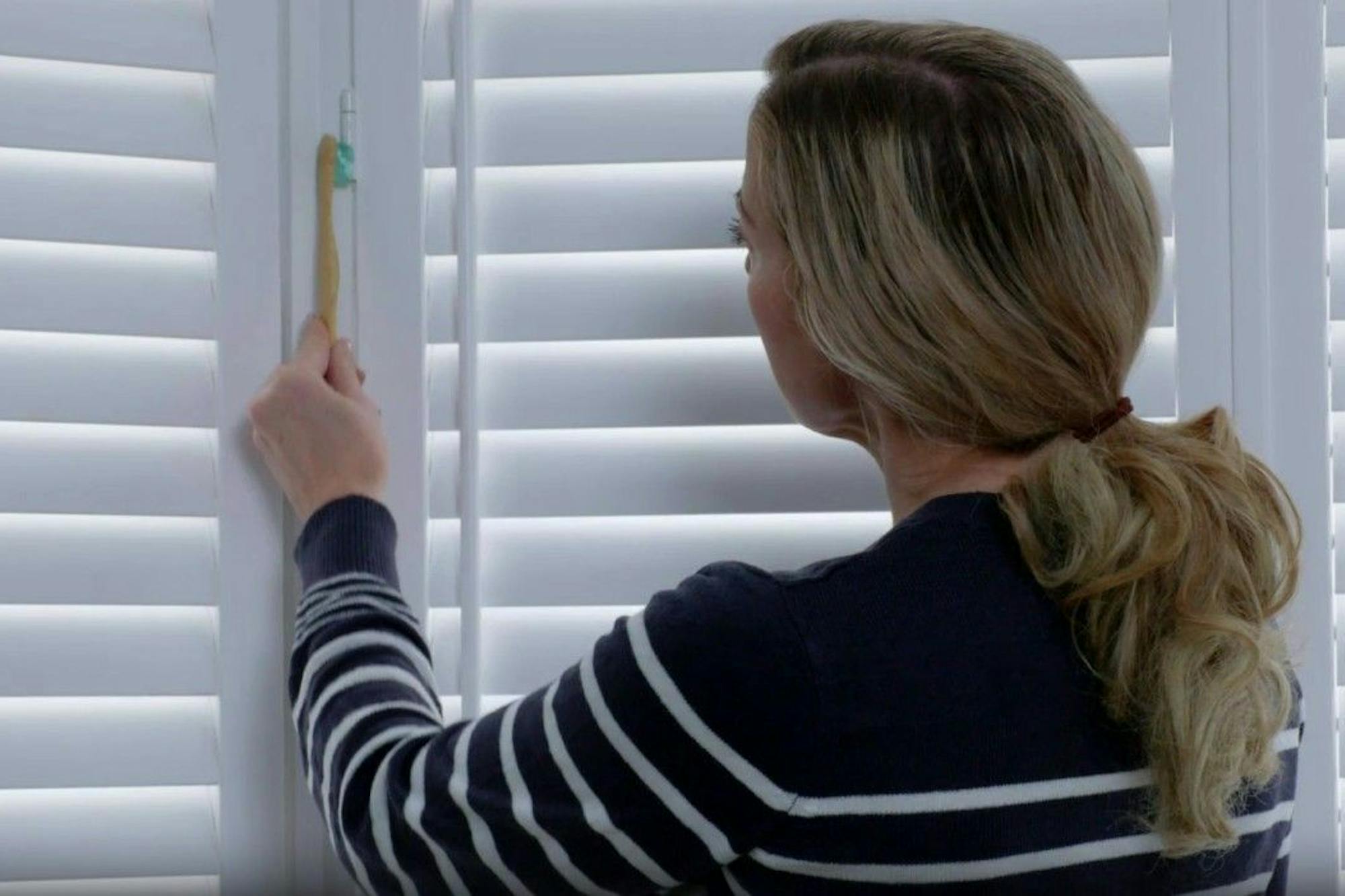 woman cleaning shutters with toothbrush