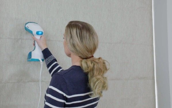 woman steam cleaning roman blind