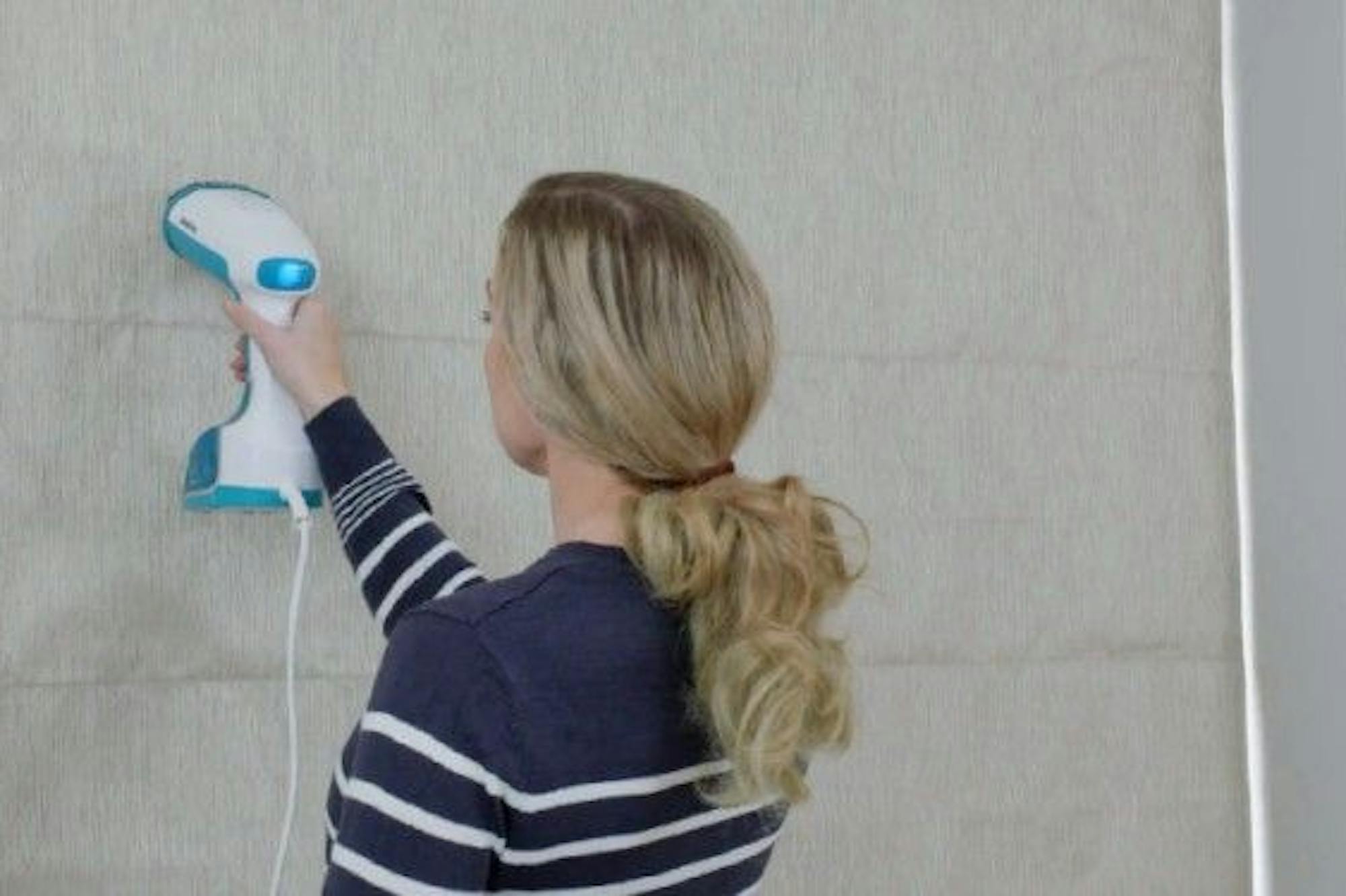 woman steam cleaning roman blind