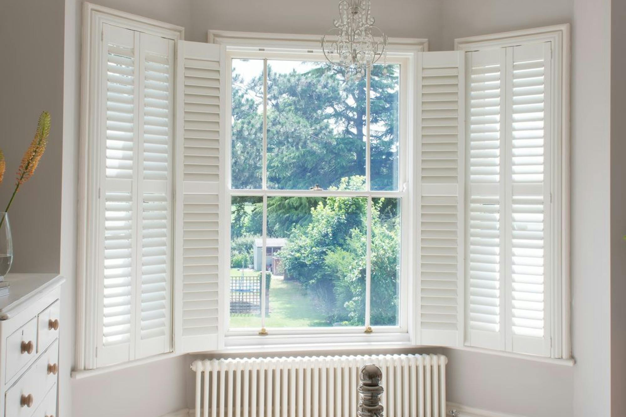 white wooden shutters on a bay window in a spacious bedroom