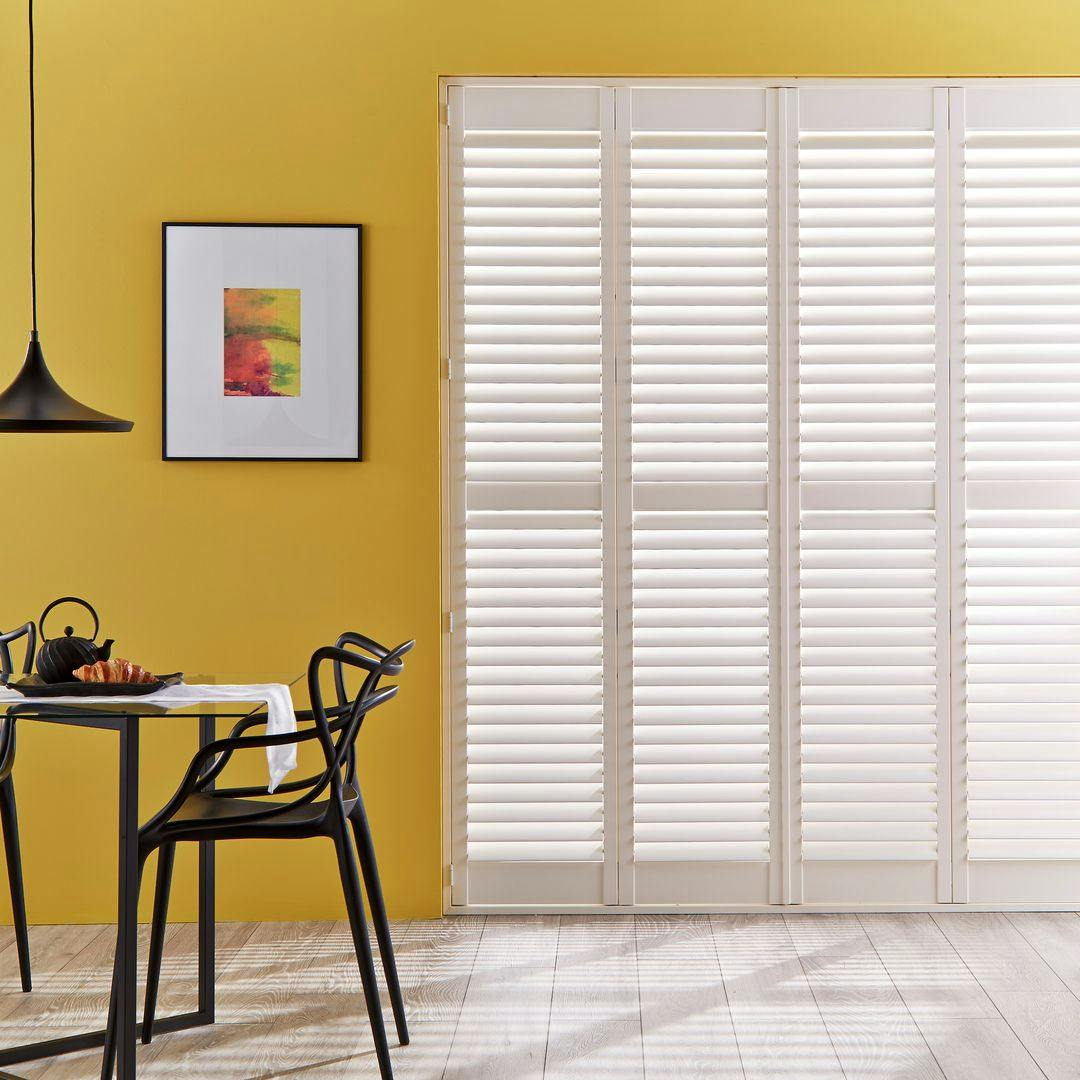 full height tracked shutters in kitchen and dining room with yellow walls