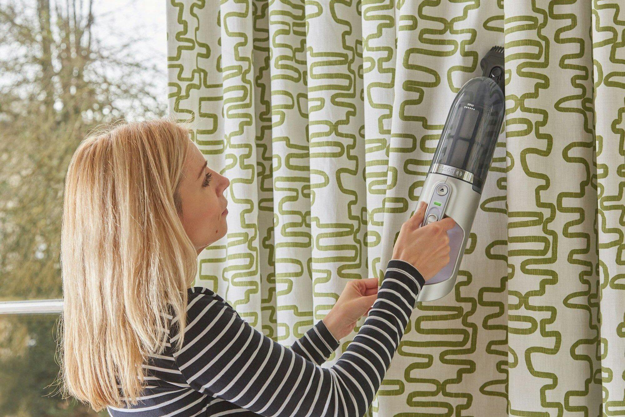 woman cleaning curtains with steamer