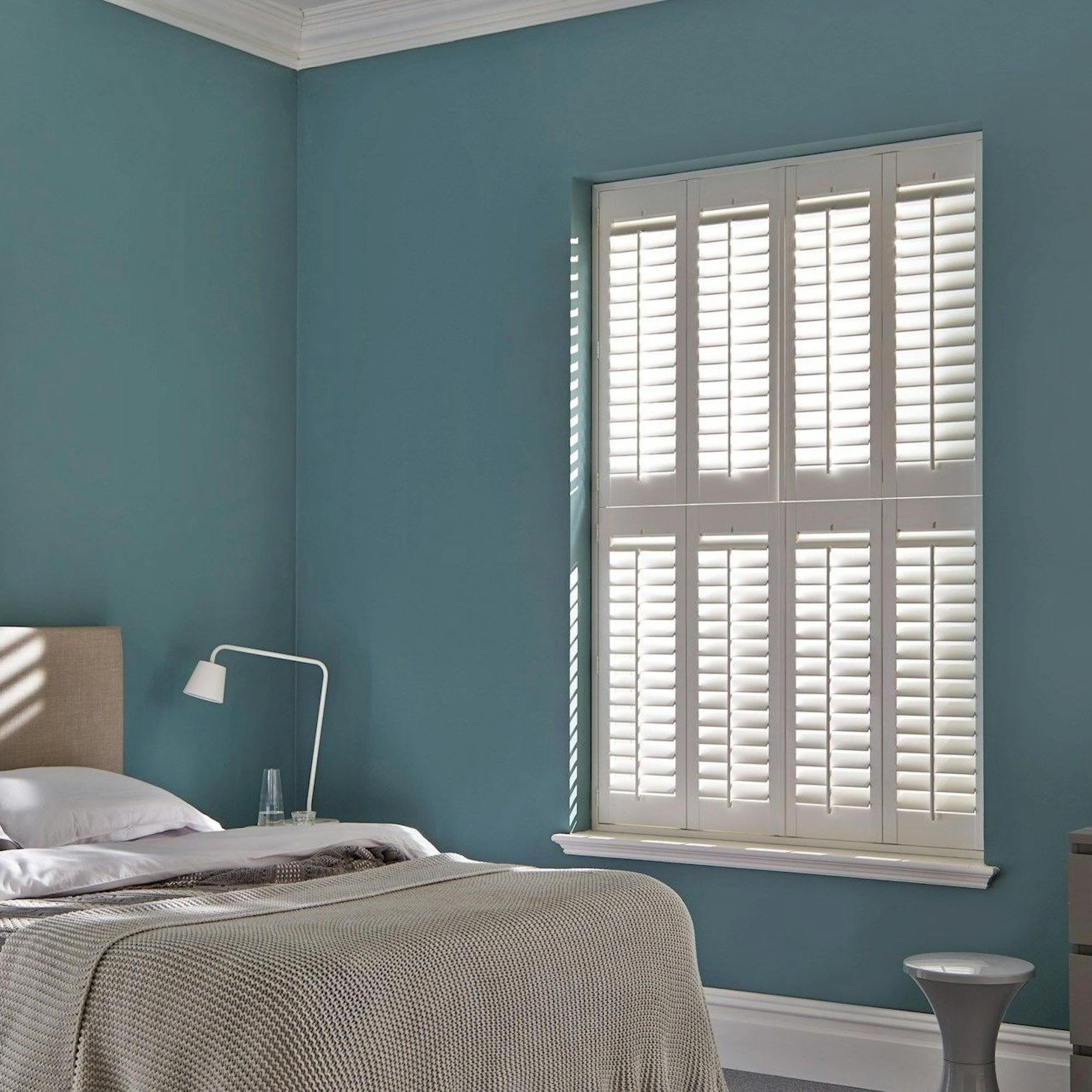 white tier on tier bedroom shutters on window with blue walls and cosy bed