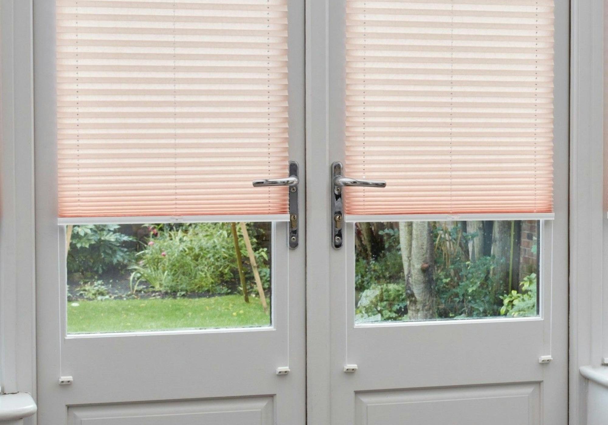 close up of light pink pleated blinds on closed french doors in conservatory