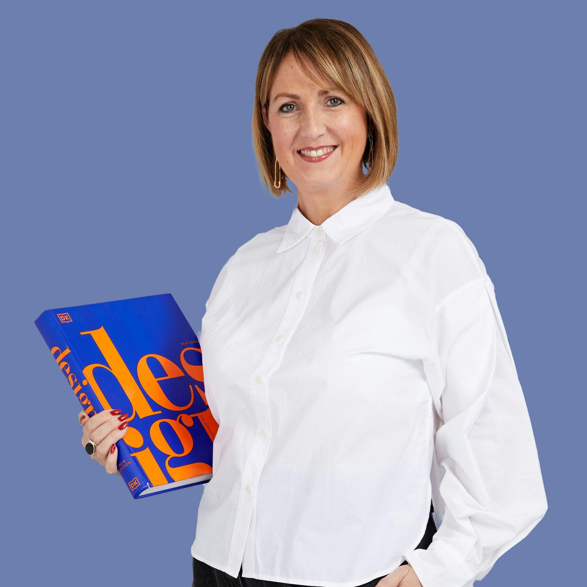 A person wearing a white shirt holds a blue book titled "design" in bold orange letters, standing against a solid blue background.