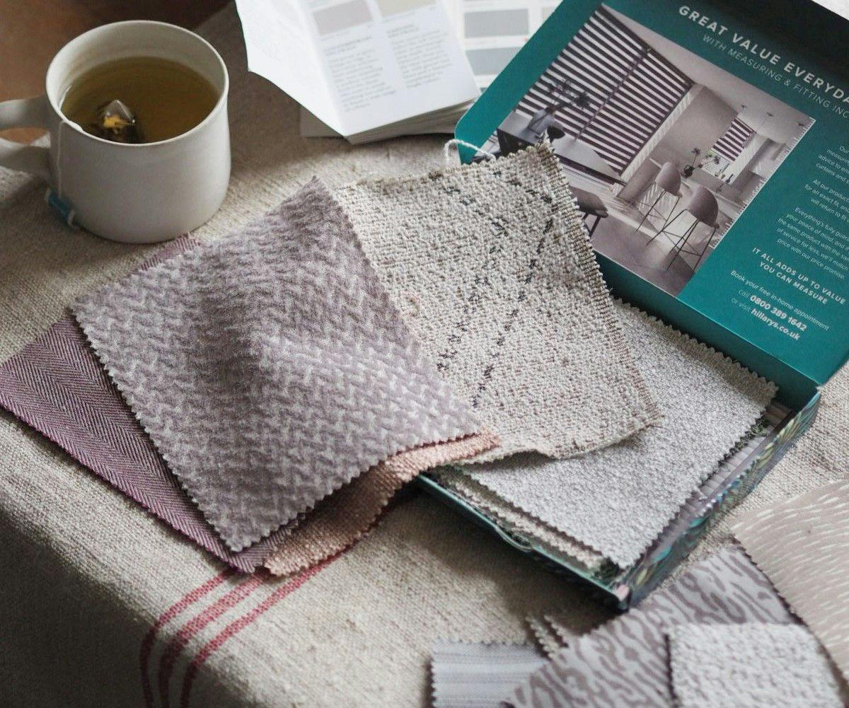 Fabric samples are spread out on a textured tablecloth next to a cup of tea. A nearby opened brochure reads: �GREAT VALUE EVERYDAY� and includes a contact number and website.