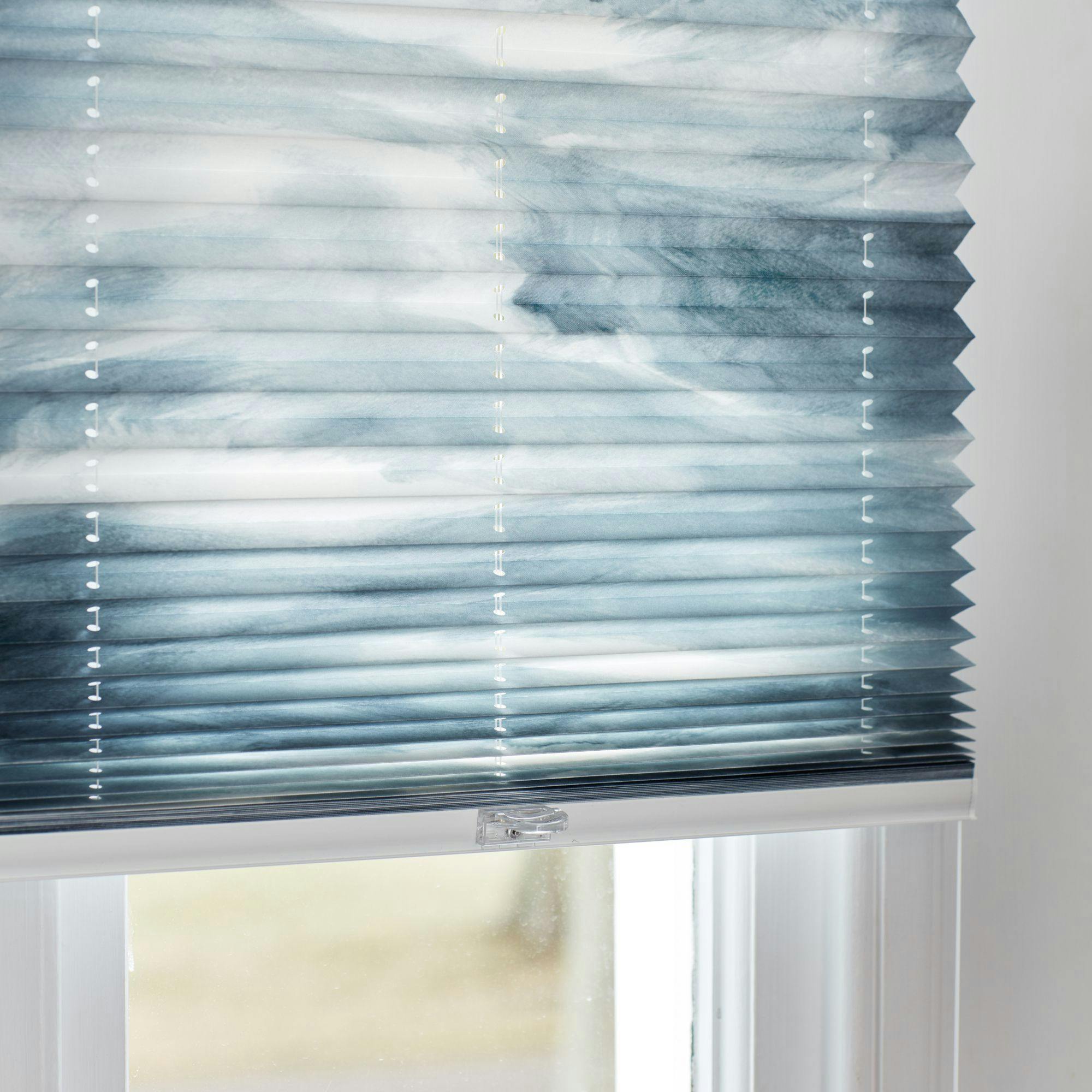 Blinds with a blue and white marbled pattern, partially drawn, cover a window. The setting appears to be indoors with soft natural light filtering through.
