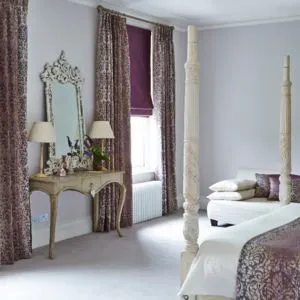 Patterned Curtains with Purple Roman blinds in guest bedroom