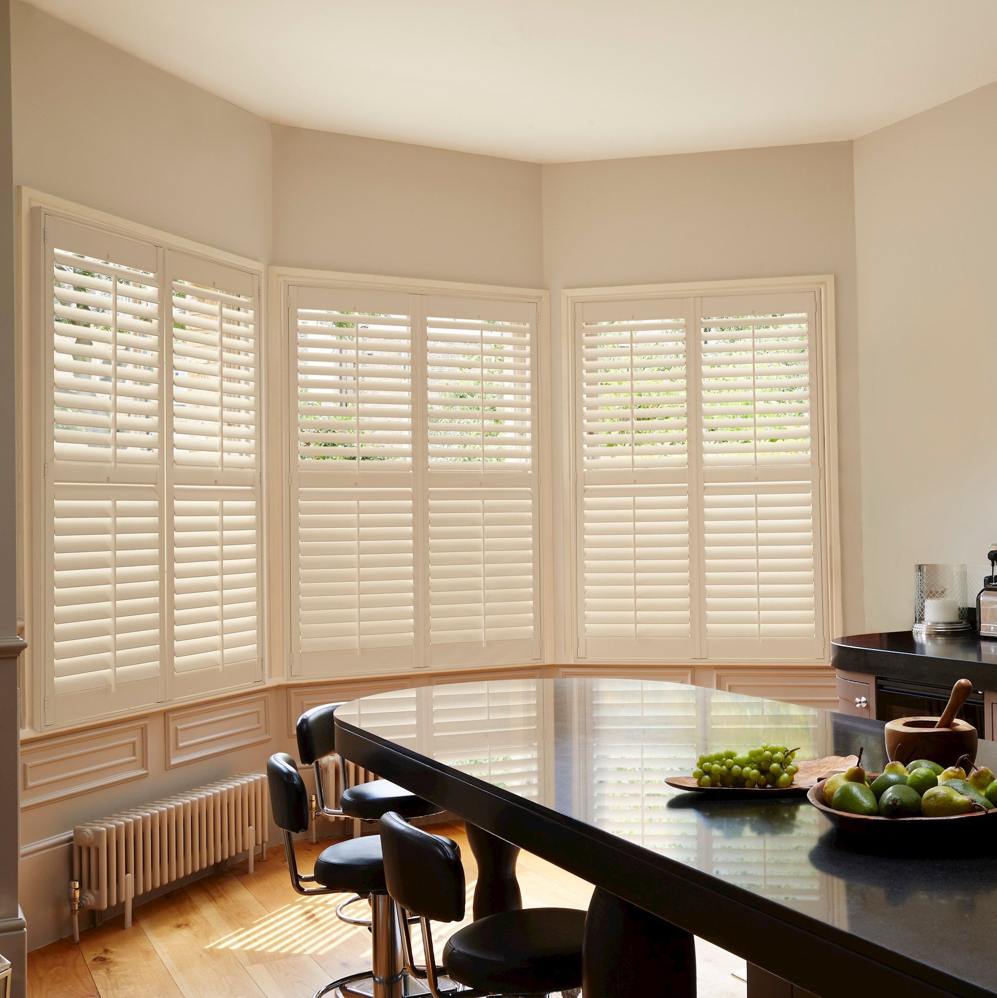 cream shutters on three curved window in a kitchen/dining area