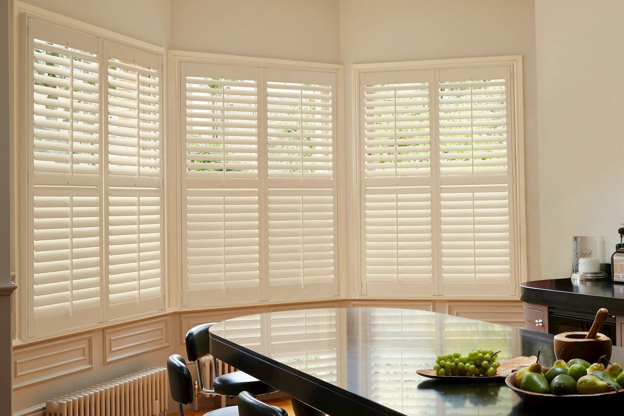 cream shutters on three curved window in a kitchen/dining area