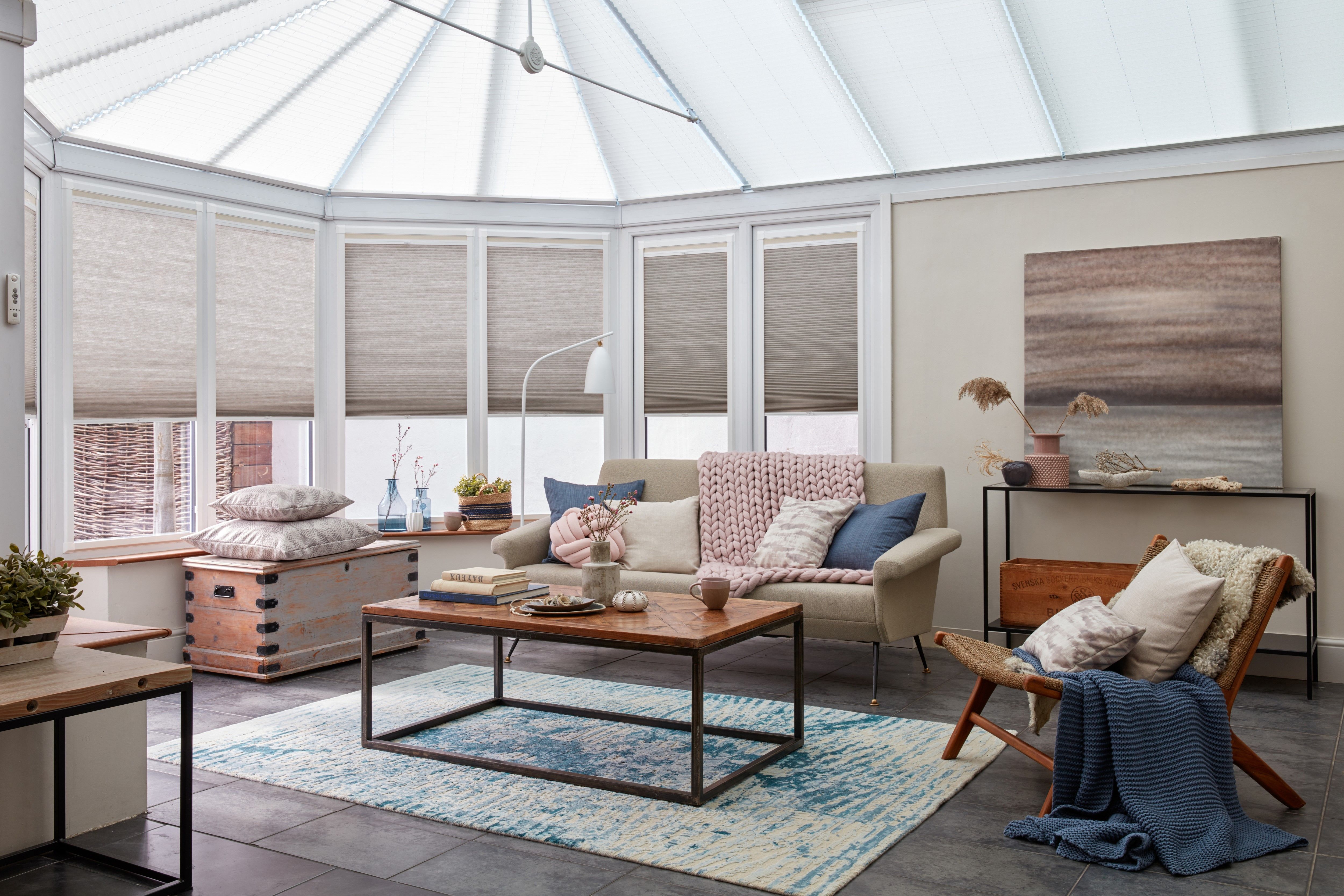 Modern open plan conservatory with cosy seating area and beige pleated conservatory blinds