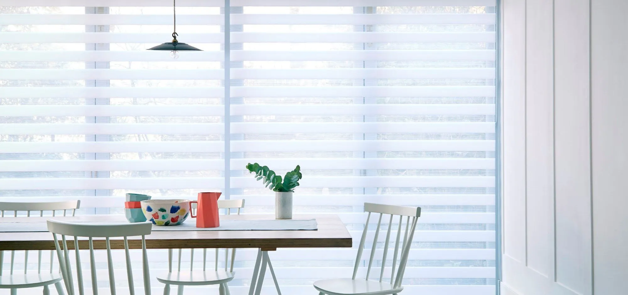 A close up of a white Day & Night blind in a kitchen with a table