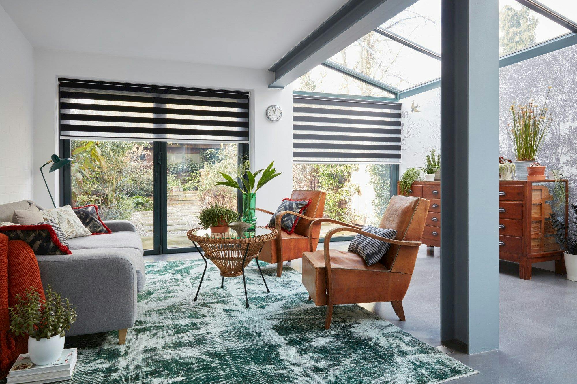 A room shot of an extension featuring wide windows covered by a black blind. 