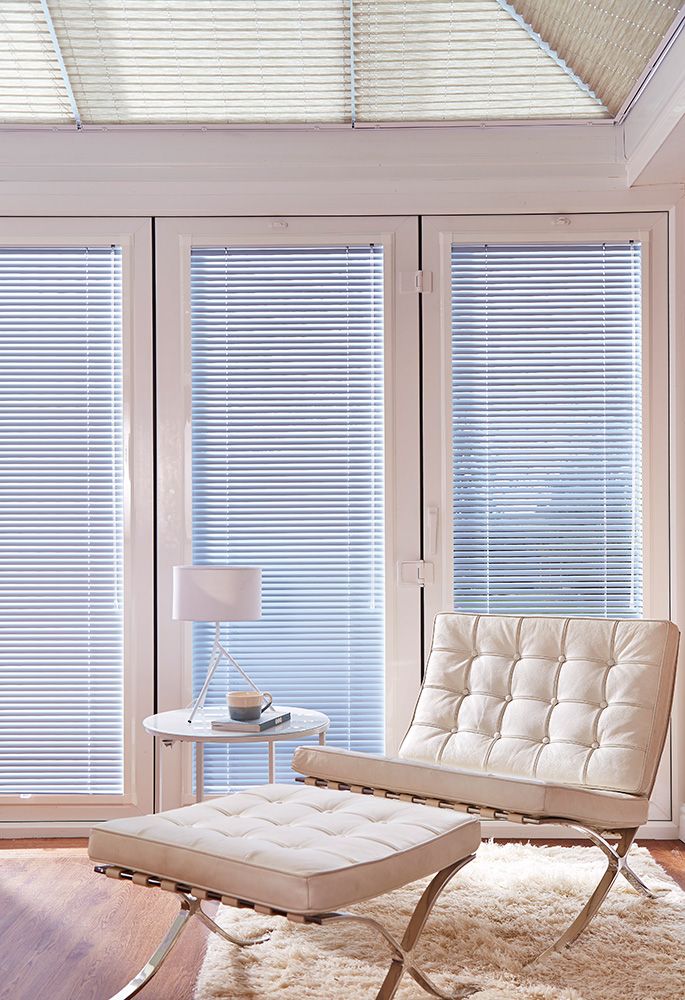 Living room lounge chair next to bifold doors with blue perfect blinds 