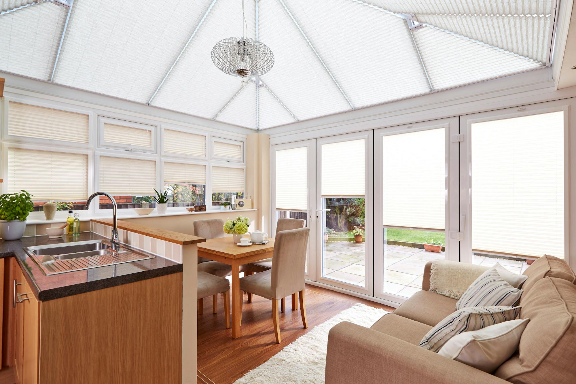 Bright open plan kitchen and dining area with white pleated conservatory blinds
