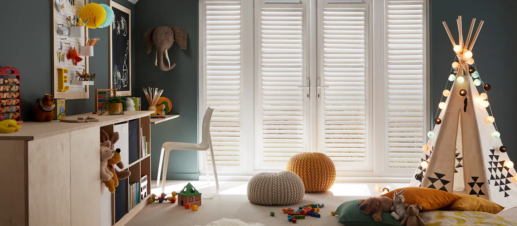 Cosy kids' playroom with a teepee, toys, storage, and soft lighting, featuring white perfect fit shutters