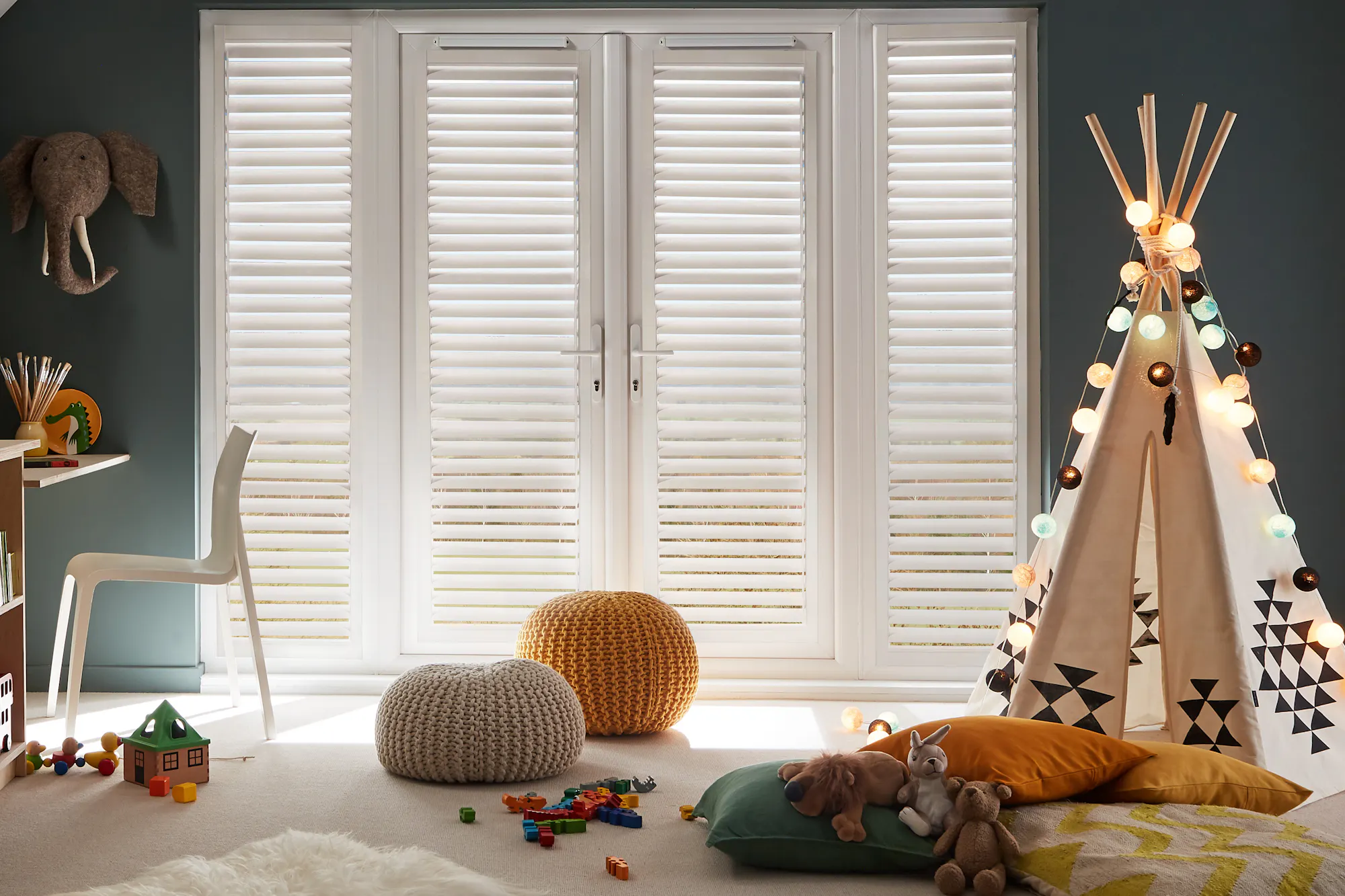 Cosy kids' playroom with a teepee, toys, storage, and soft lighting, featuring white perfect fit shutters