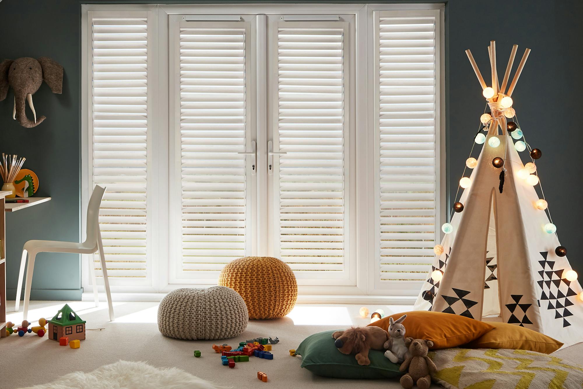 Cosy kids' playroom with a teepee, toys, storage, and soft lighting, featuring white perfect fit shutters