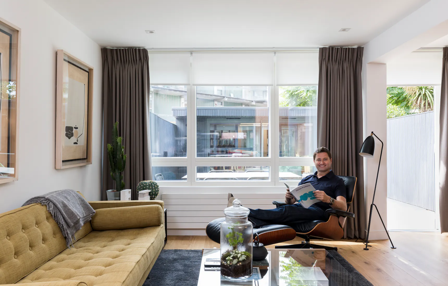 Modern living room with grey motorised roller blind and Bardot grey curtains, featuring a neutral color palette and soft, ambient lighting.