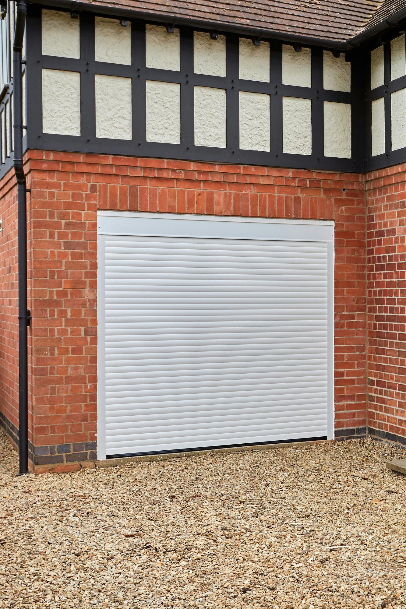 Red brick and Tudor style house with integrated garage at abutting corner with a white garage door.