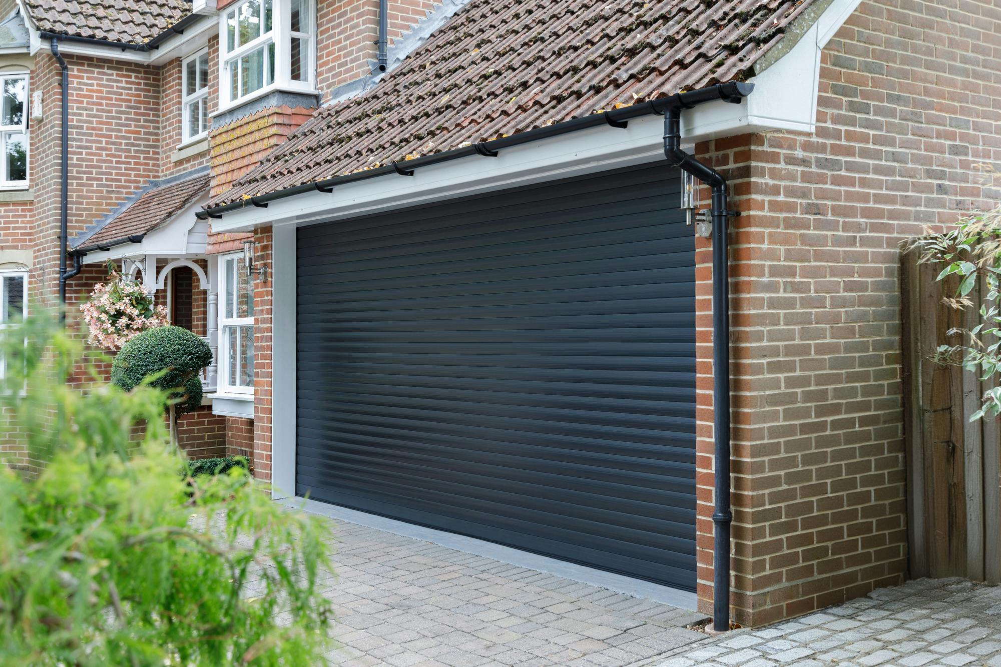 Dark brick house with dark grey garage door at centre of image.
