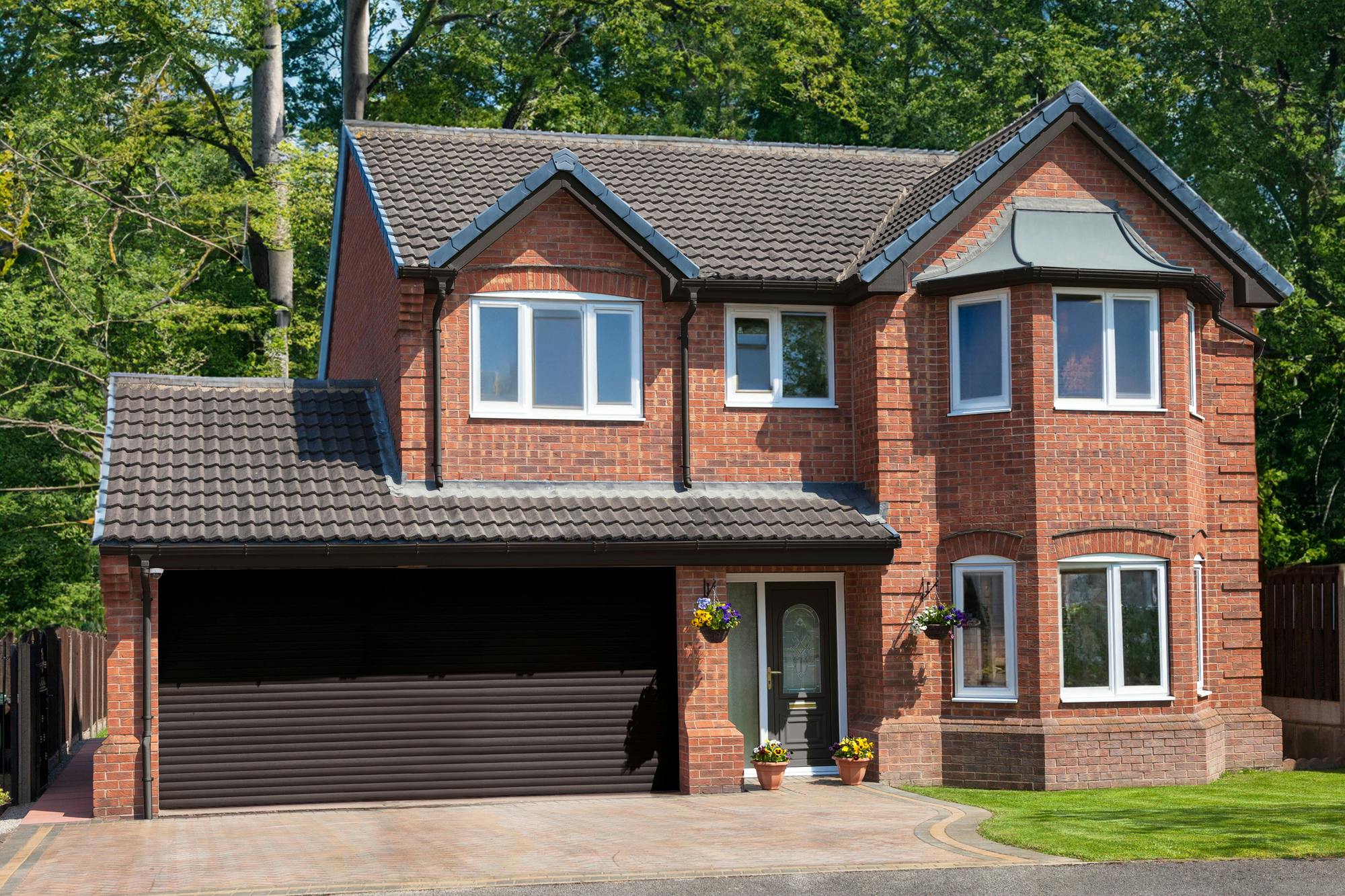 Large traditional brick house with apex windows and double-width internal garage with dark brown roller door that matches the front 
