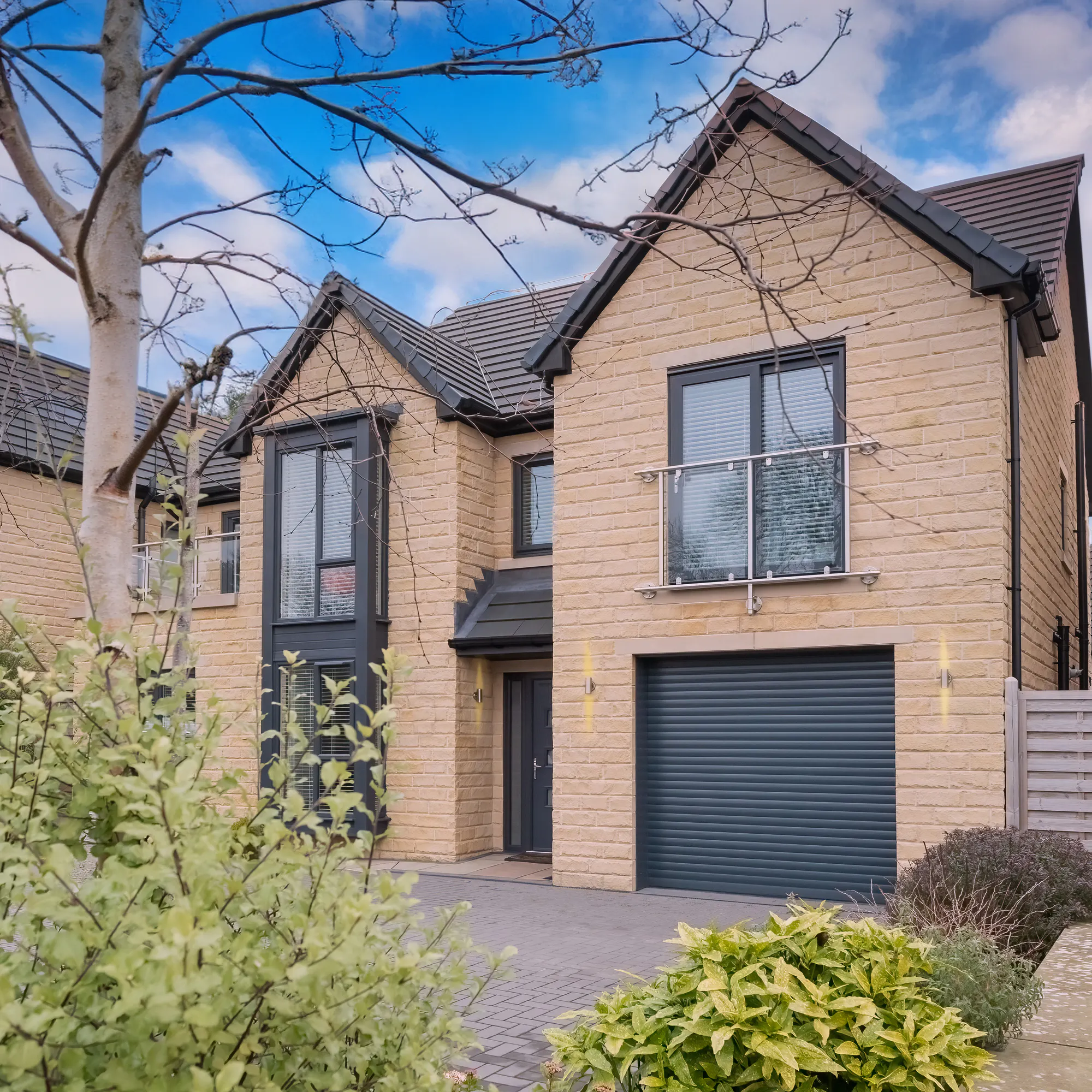 Beige brick townhouse style property with integral garage and garage door in dark grey matching door and window frames.