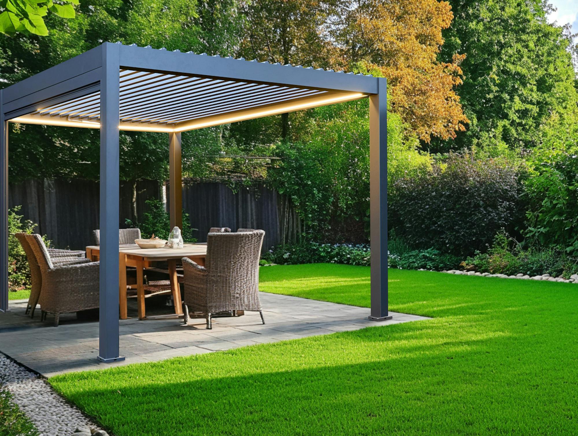 Garden exterior with paved patio surrounded by a lawn and on the patio a freestanding grey pergola with fabric roof over four chairs and a table.