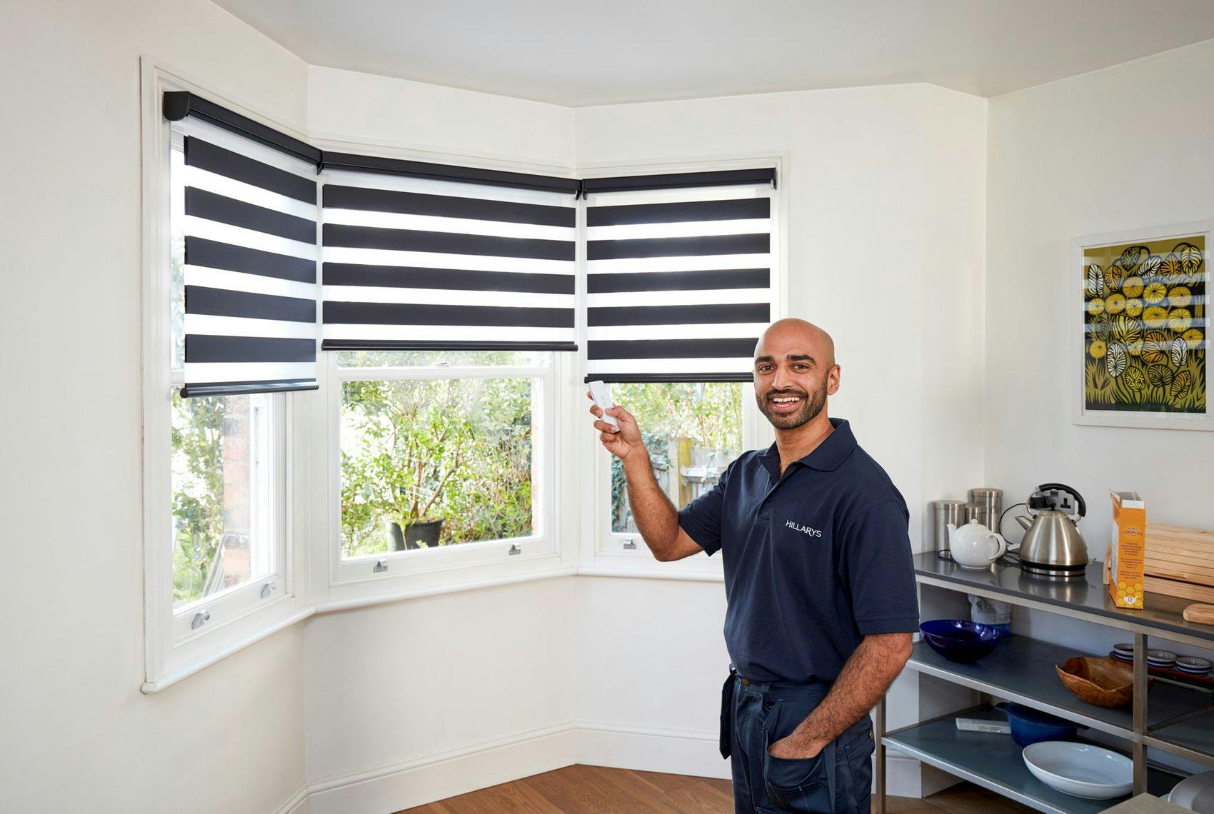 Hillarys advisor with a branded uniform posing in front of a window with Day and Night blinds on it