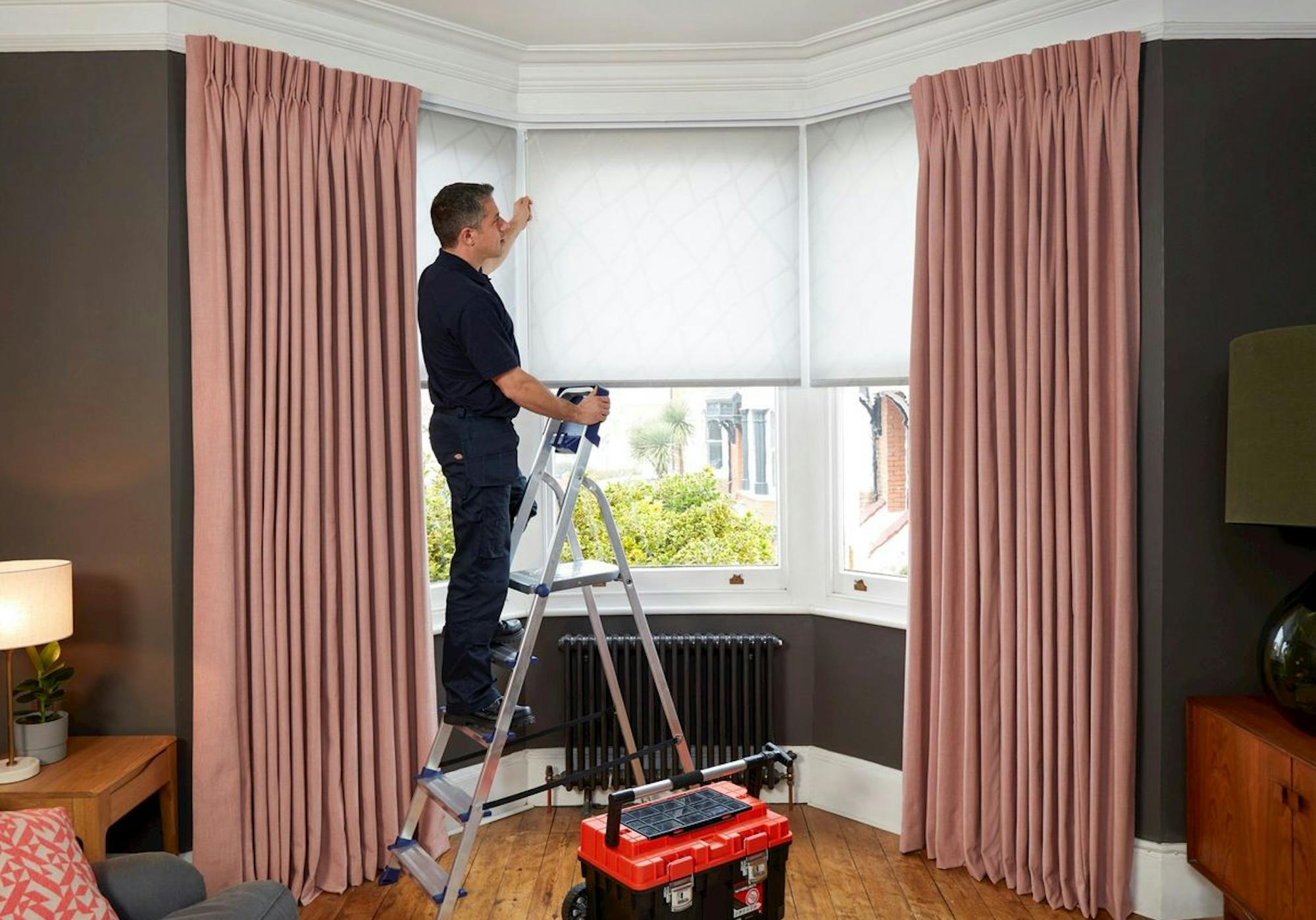 Hillarys advisor helping to fit white roller blinds on a window