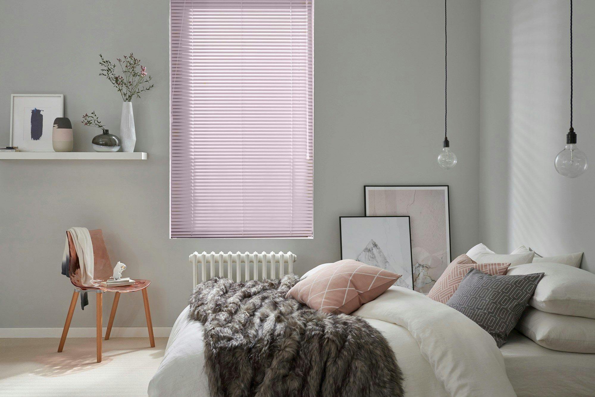 Sugar-pink aluminium venetian blind fully lowered on a window, slats tilted open to let daylight stream into the room.