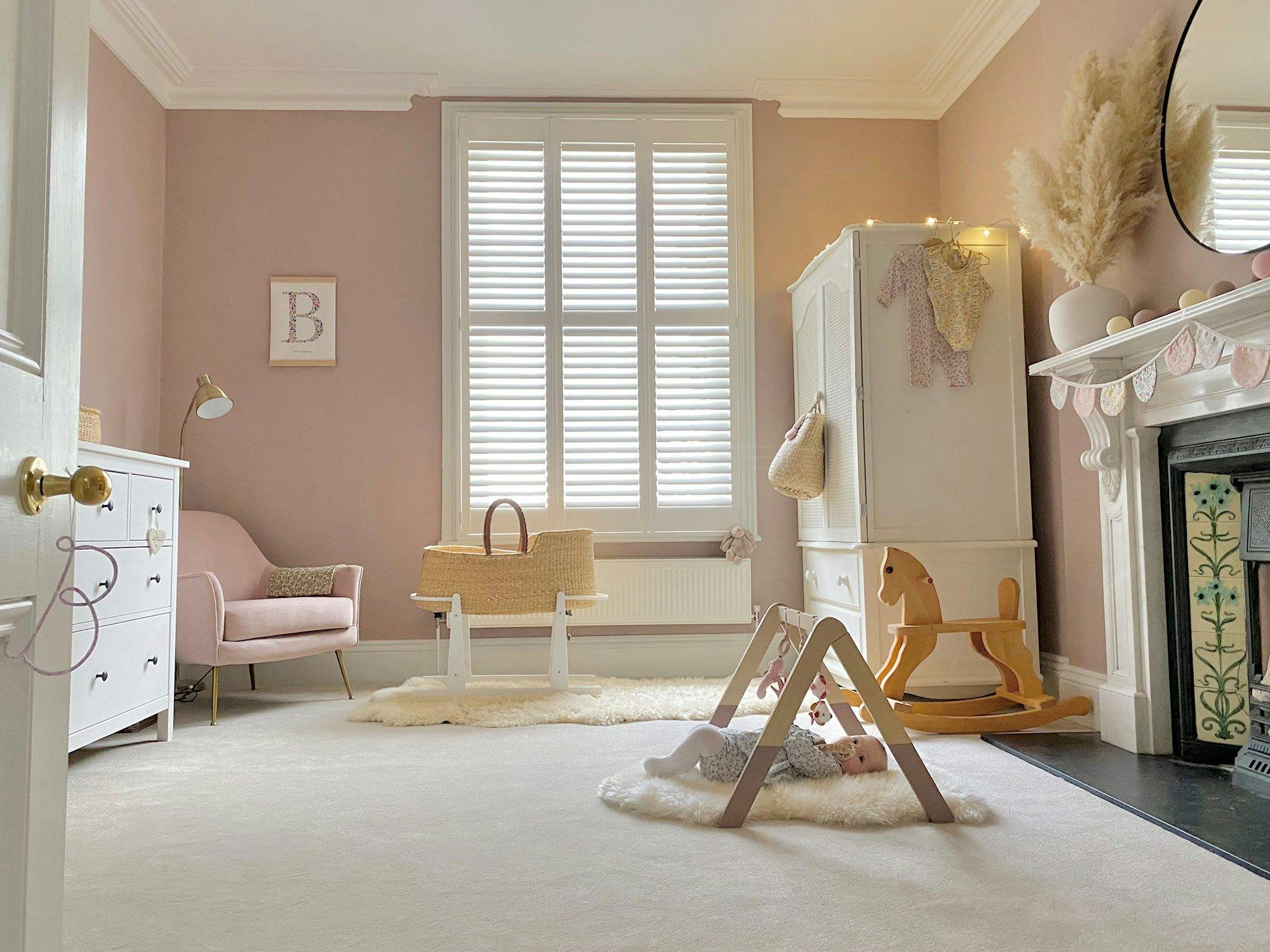 full height white shutters in pastel themed nursery with rocking horse in the middle of the room