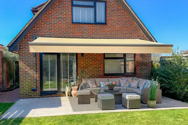 Cream Awning on a brick house on the back of a garden with few garden furniture items